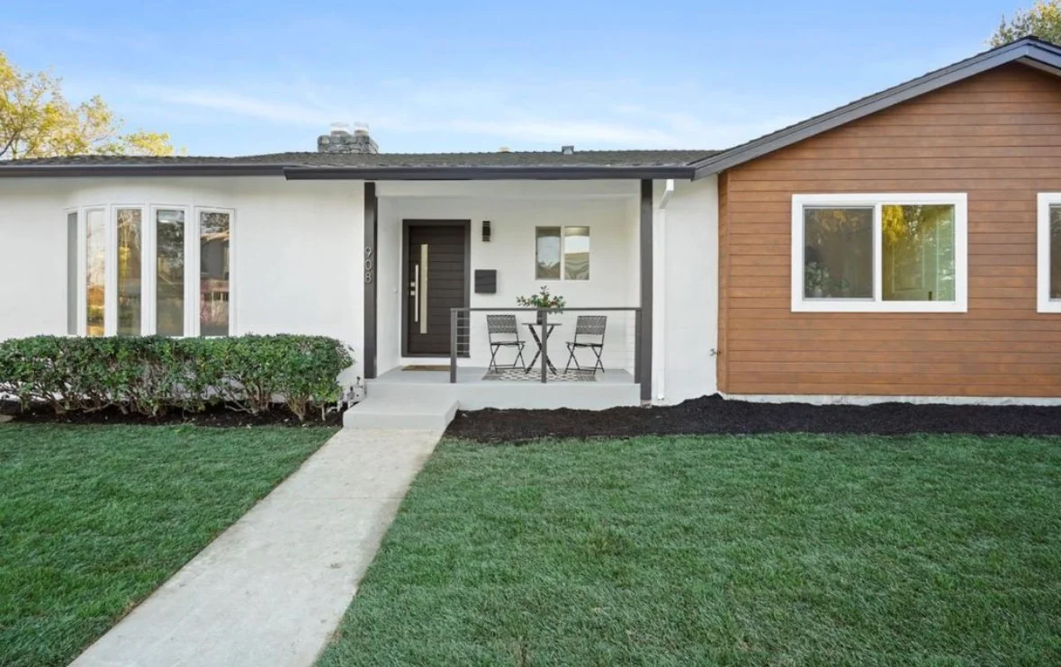 Modern home exterior with white stucco, cedar siding, black metal accents, and covered porch entry