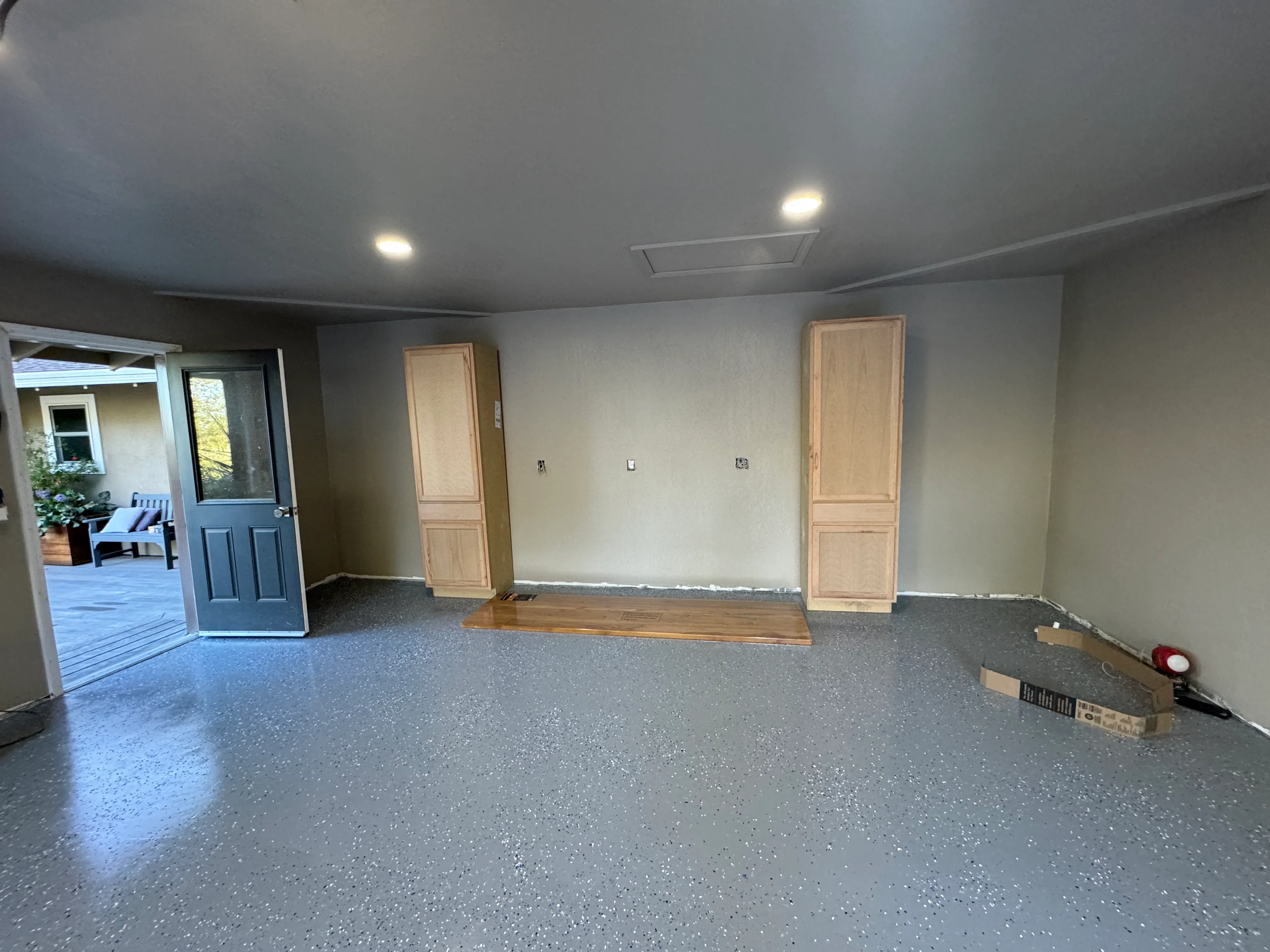 Finished garage interior with epoxy floor, drywall, recessed lights, and wood doors