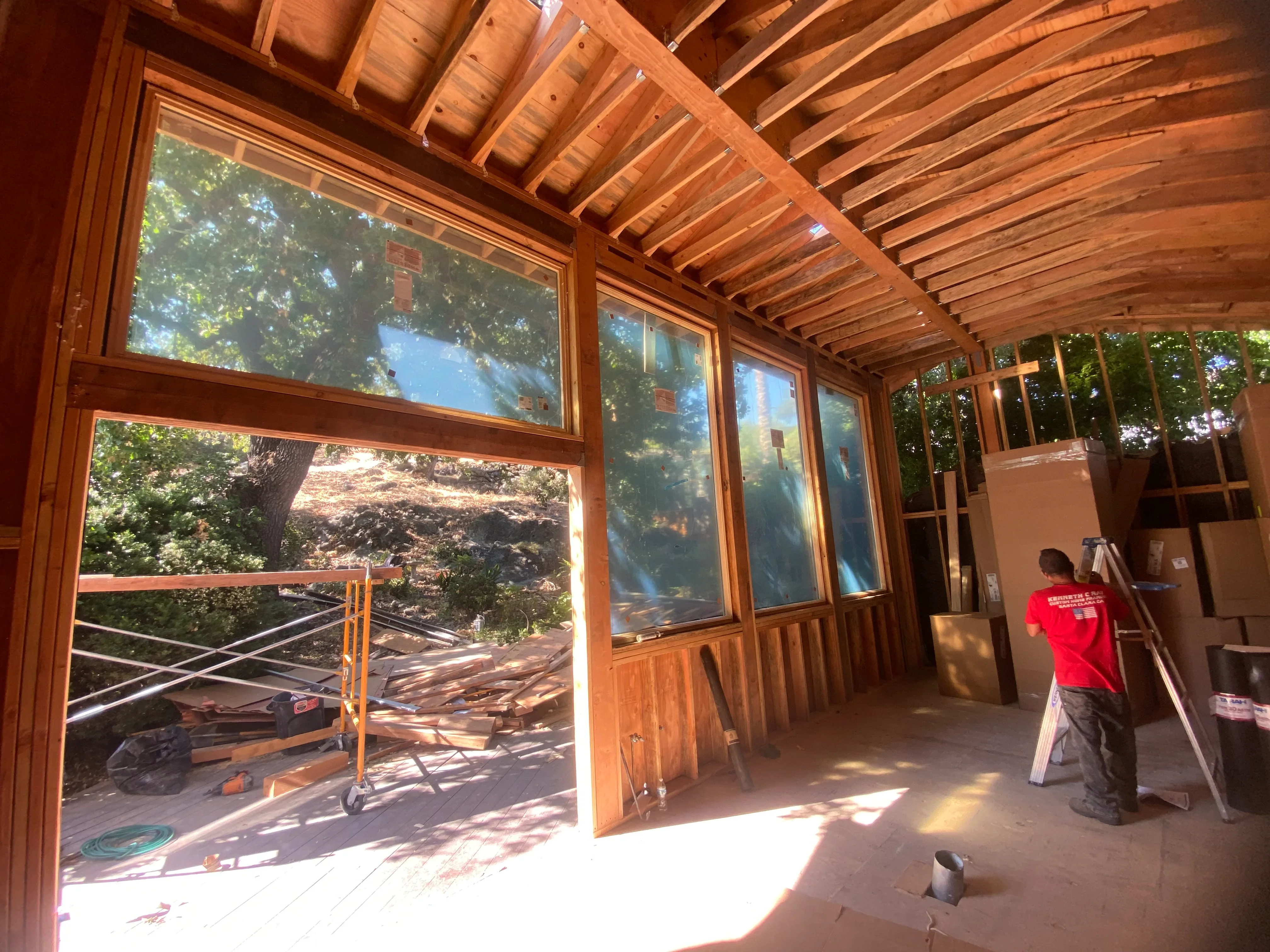 Interior of new wood sunroom with exposed beams, large windows, and glass doors overlooking trees