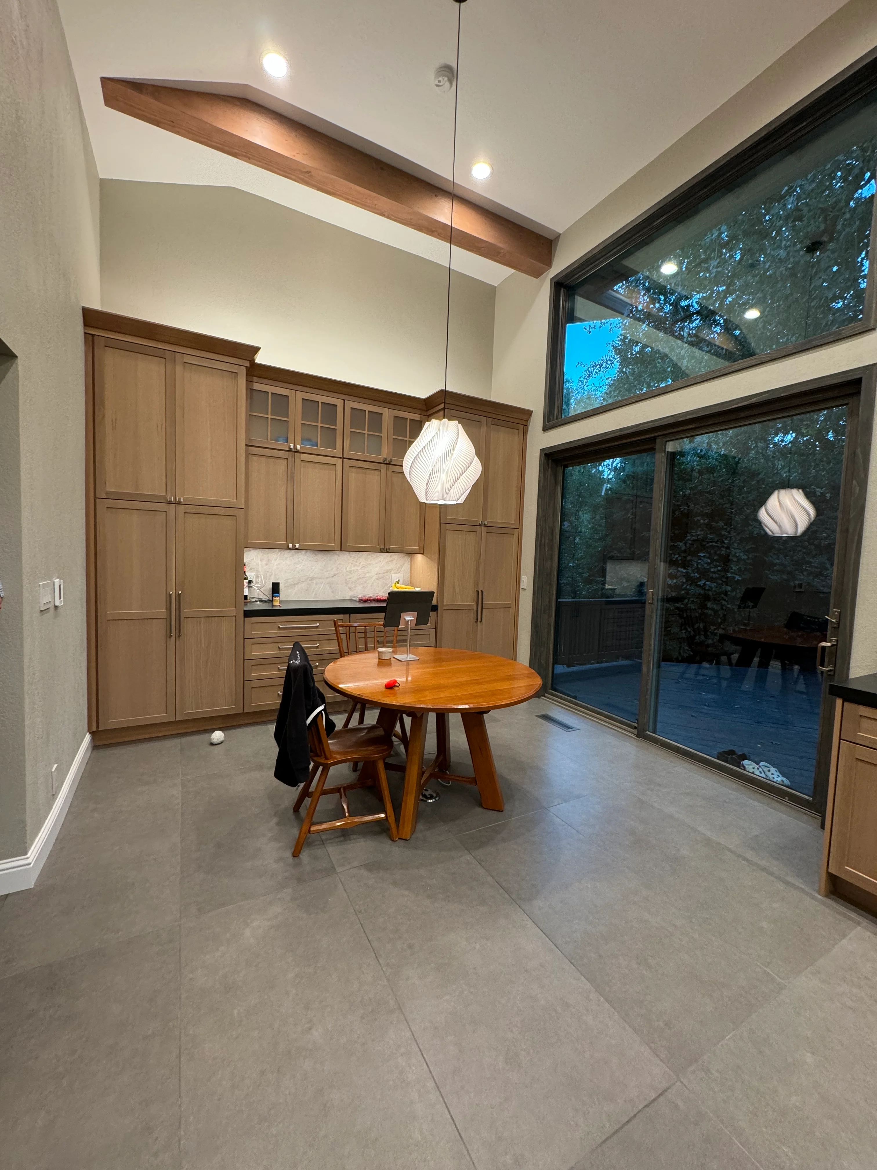 Modern kitchen with walnut cabinetry, marble backsplash, concrete flooring, and large sliding glass doors