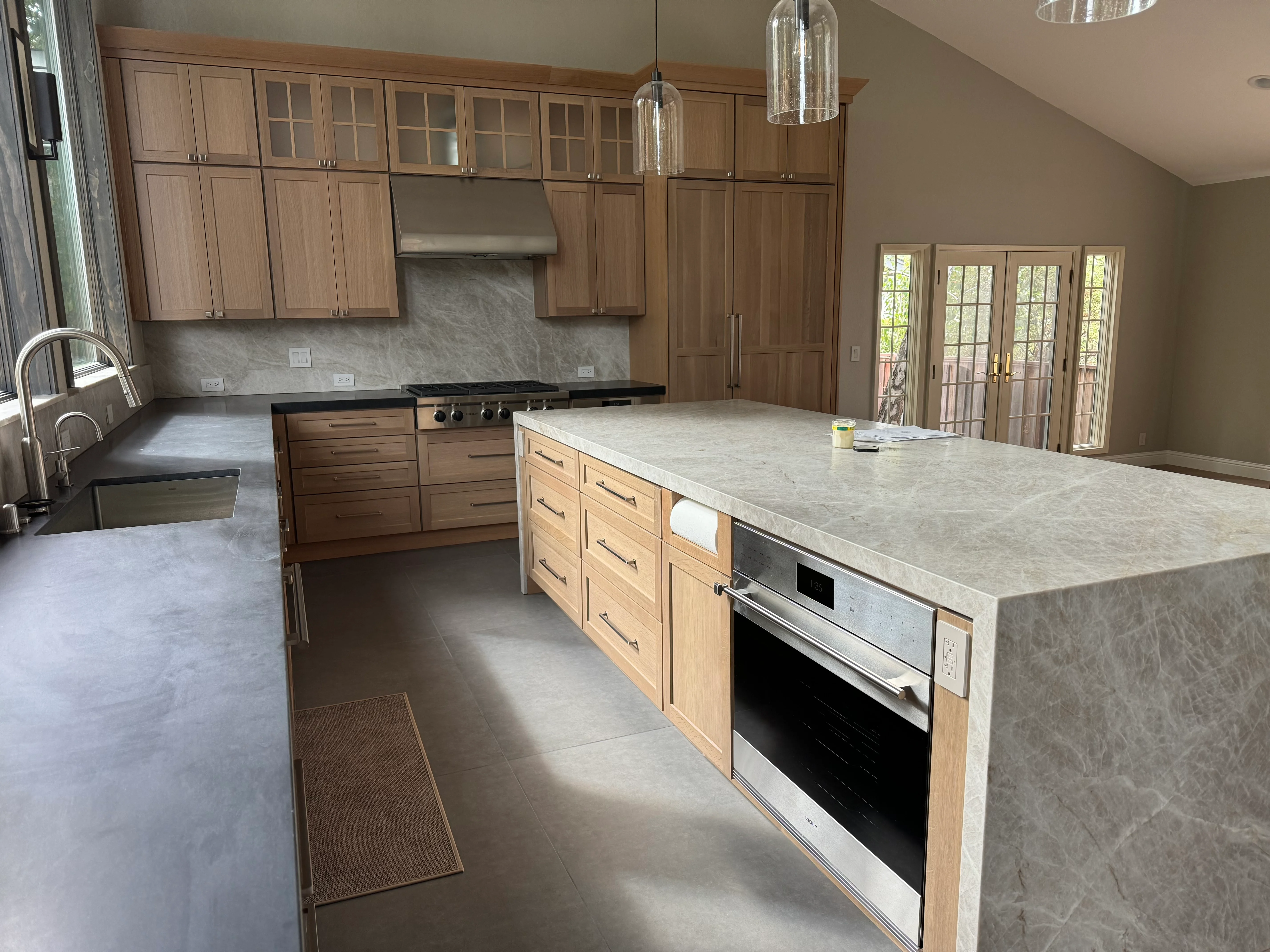 Modern kitchen with walnut cabinets, quartz countertops, island, and stainless steel appliances