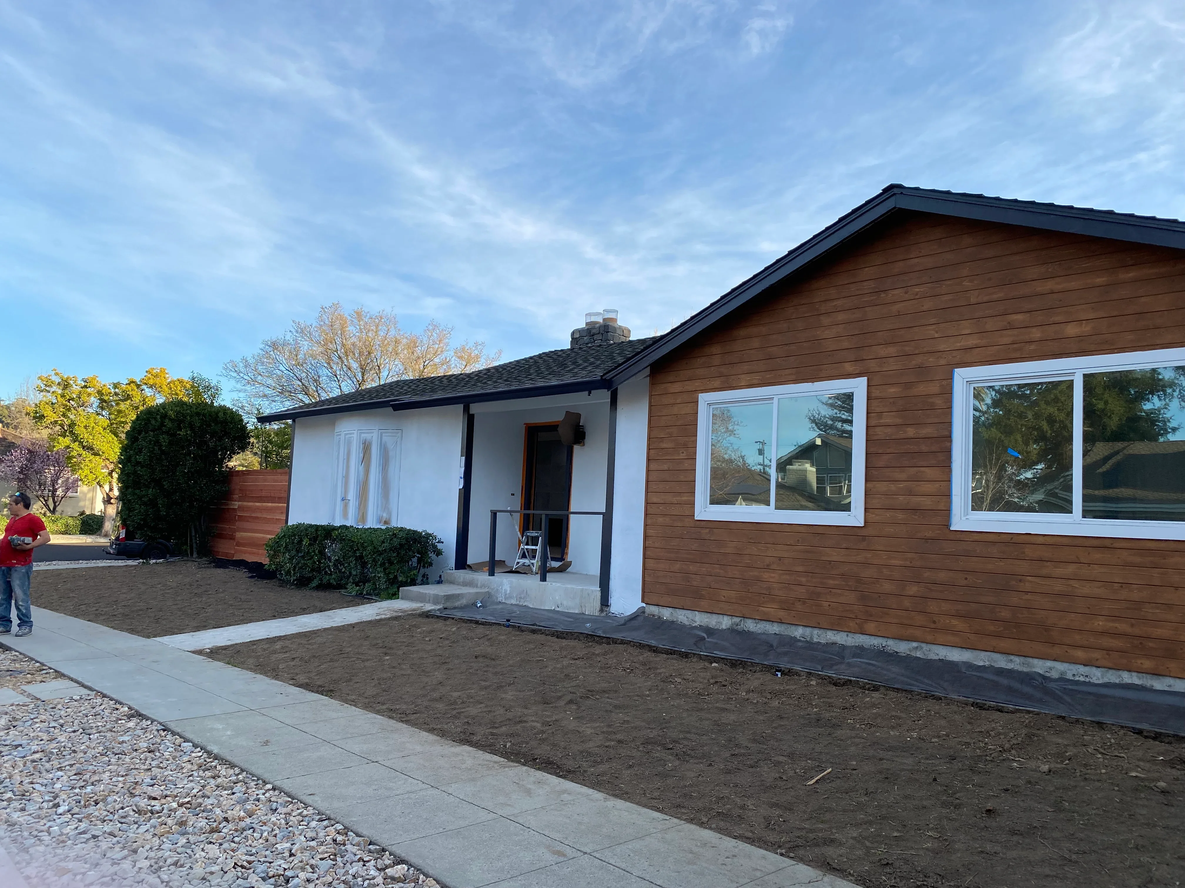 Modern home exterior with brown wood siding, white-framed windows, and updated entry