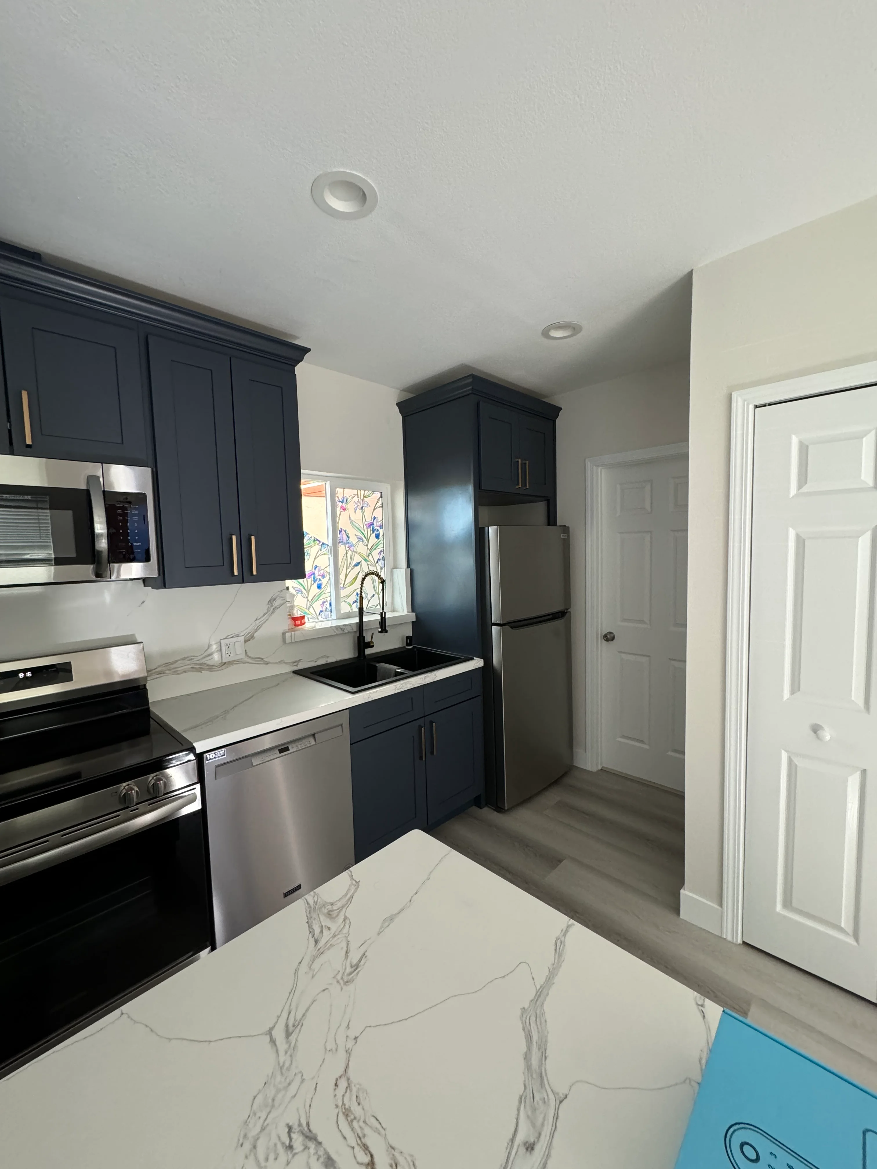 Navy cabinetry kitchen with marble quartz counters and stainless steel appliances