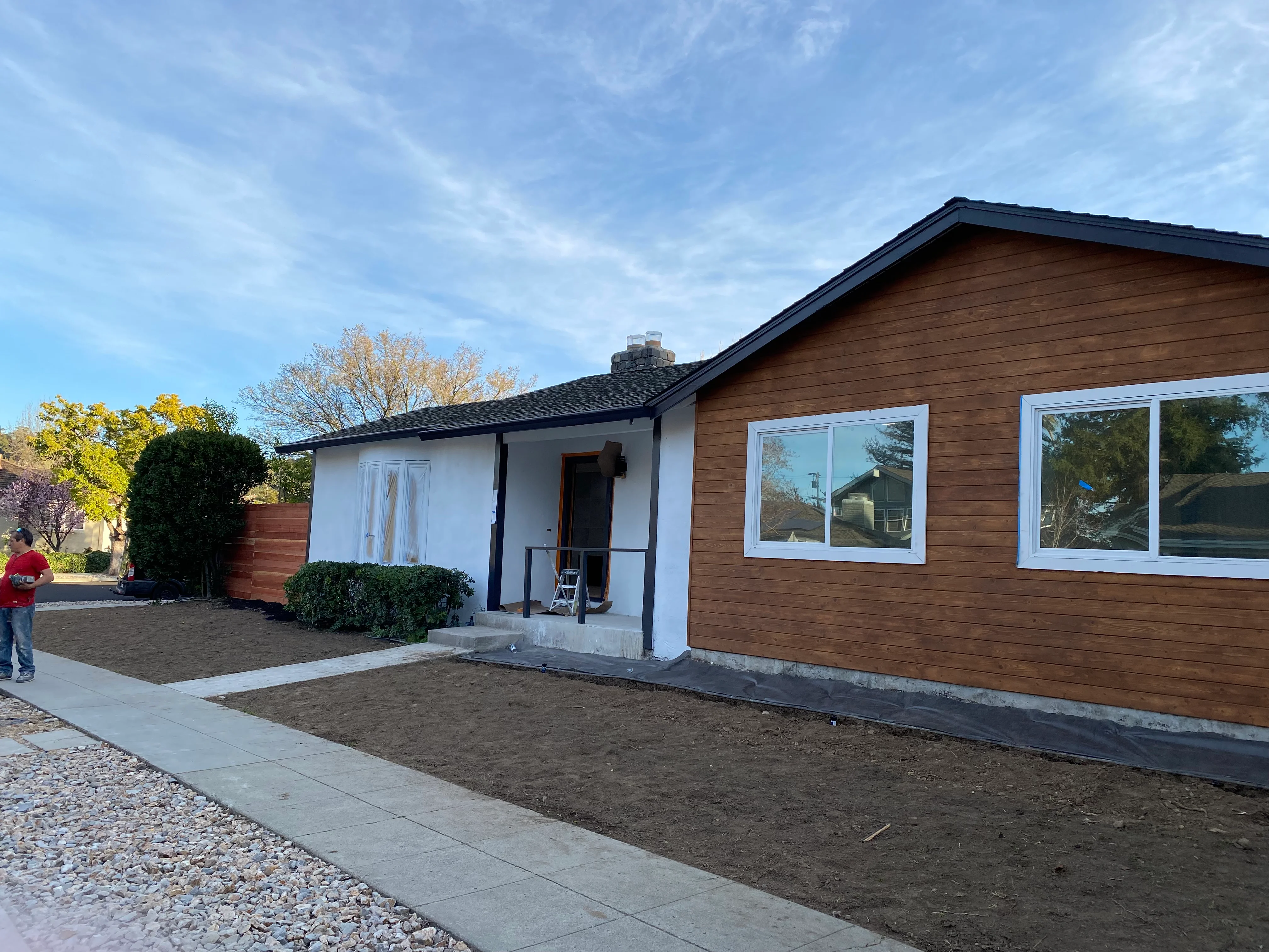 Modern home with cedar siding, white trim, large windows, and new concrete foundation