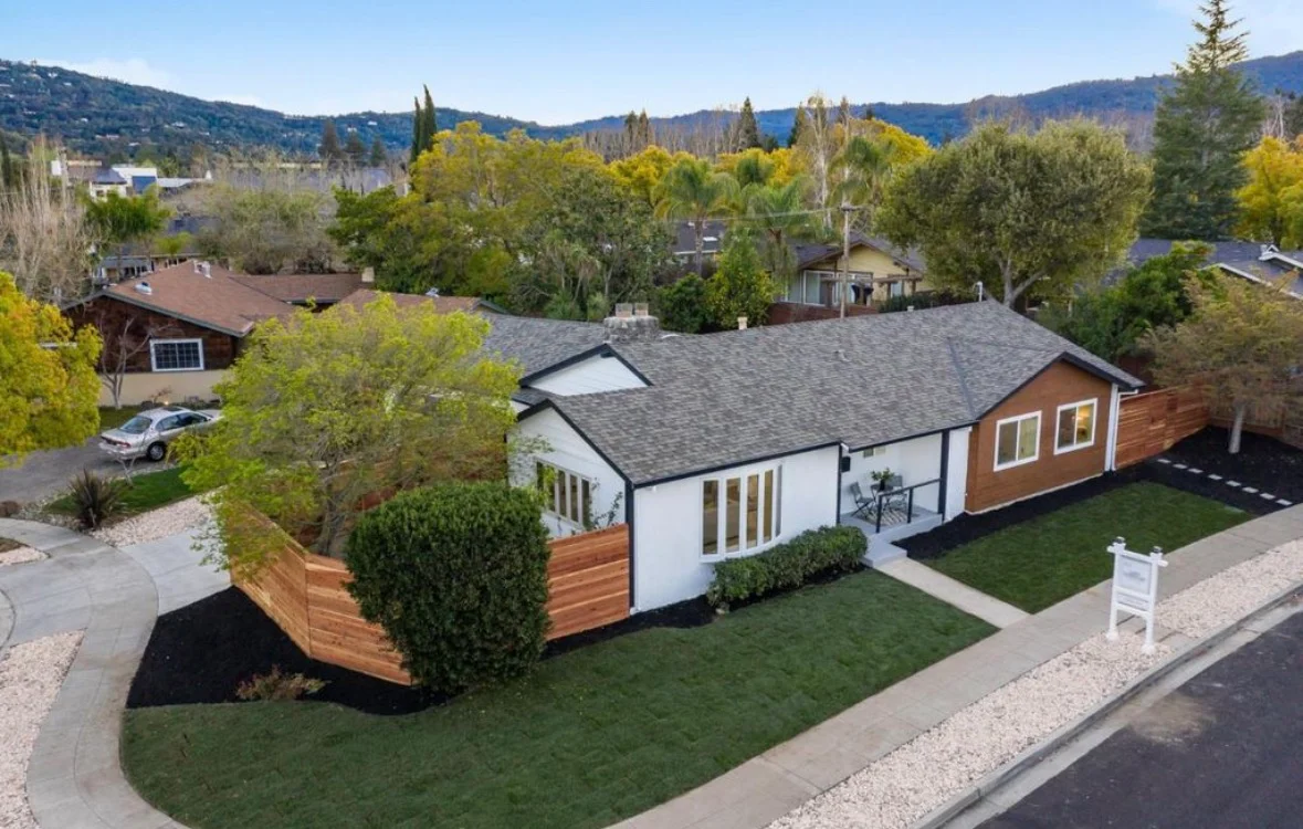 Modern home with gray composite roof, white and cedar siding, new windows, and landscaped yard