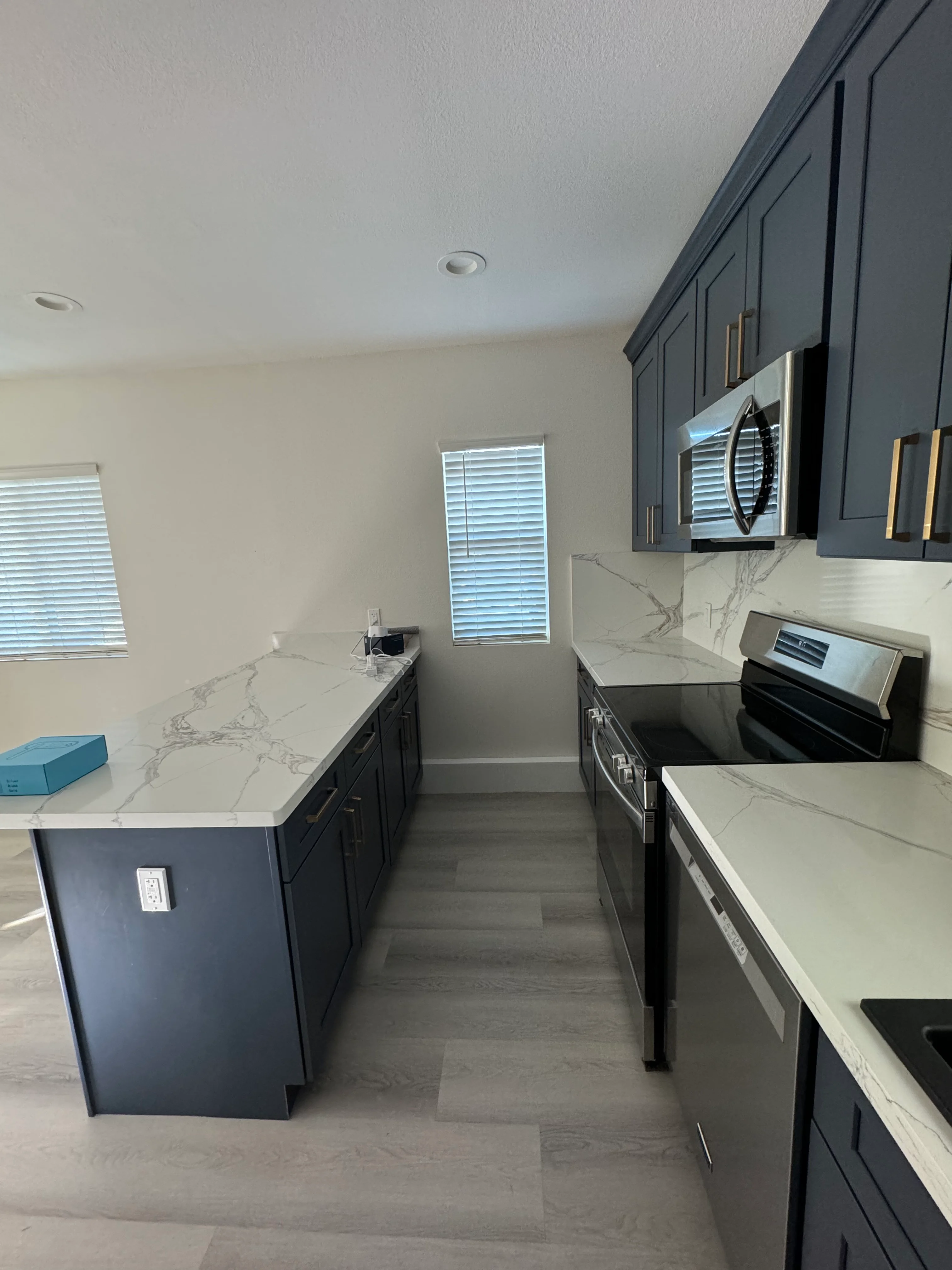 Dark cabinetry kitchen with marble quartz counters, stainless appliances, and island