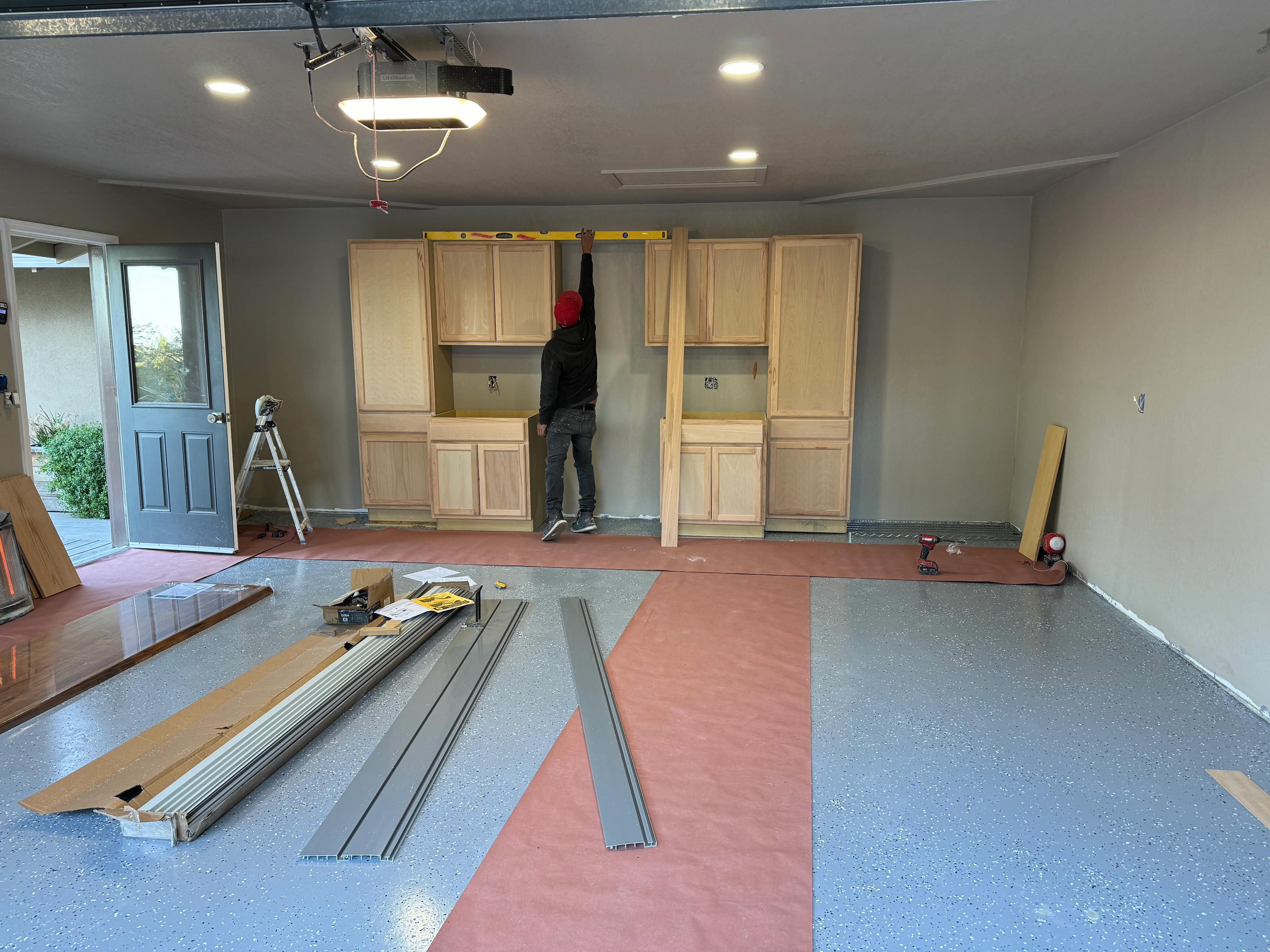 Garage interior with wood cabinetry, epoxy flooring, and LED lighting installation in progress