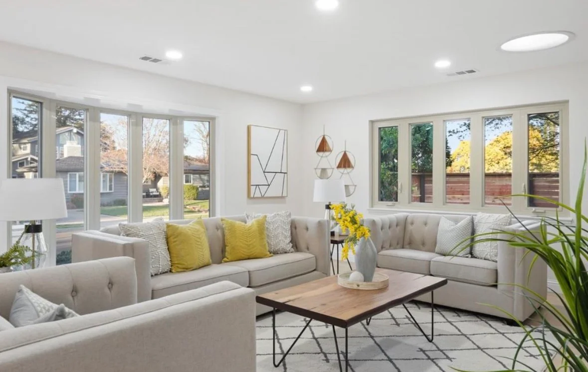 Bright living room with multi-panel glass doors, recessed lighting, beige upholstered furniture, and wood coffee table