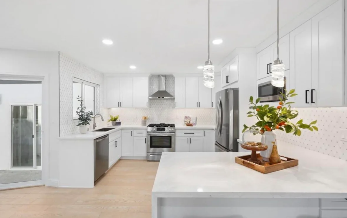 Modern white kitchen with island, stainless steel appliances, and geometric backsplash tile