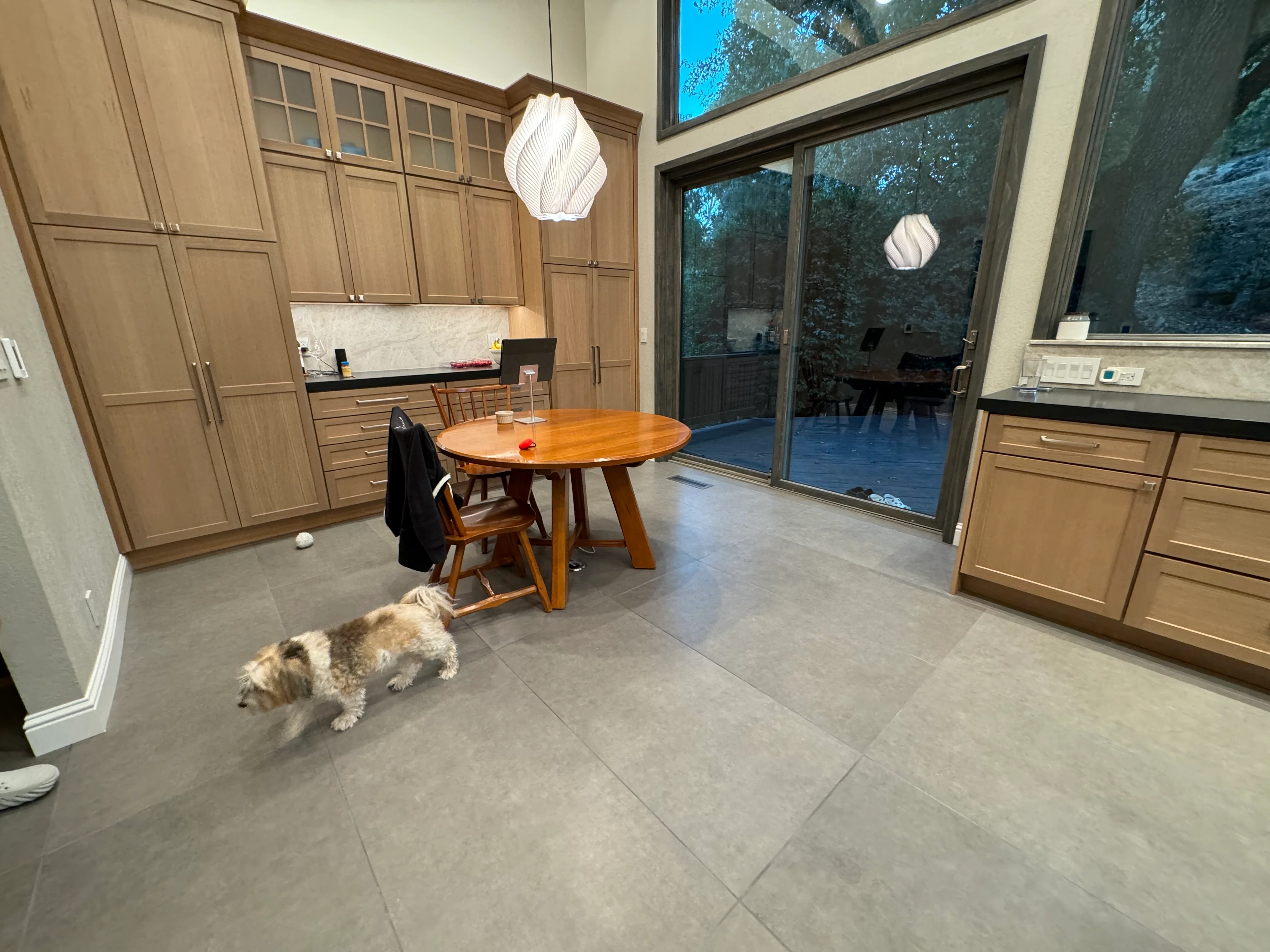 Kitchen with wood cabinetry, gray tile flooring, marble backsplash, and sliding glass patio doors