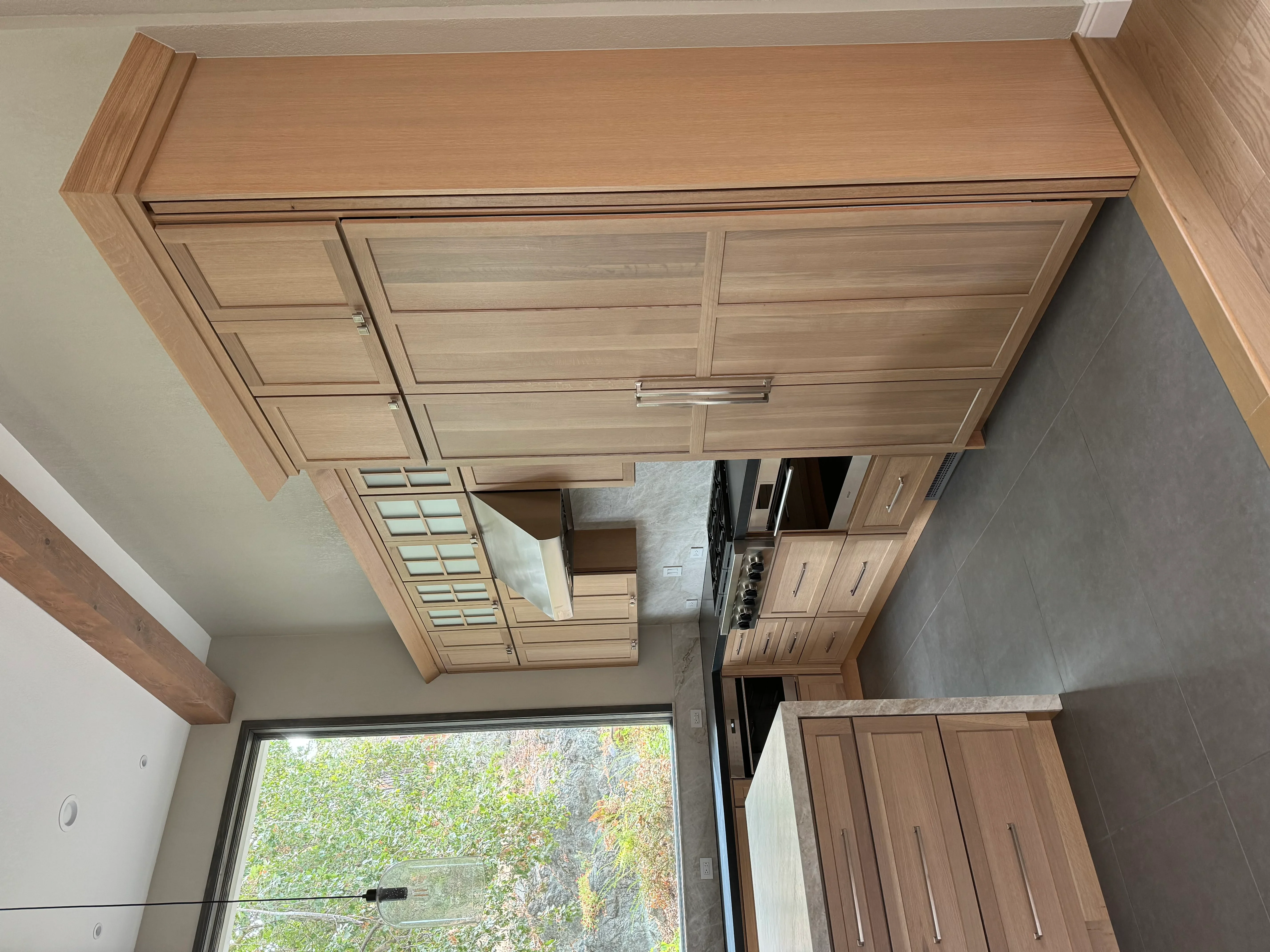 Light oak kitchen cabinets with shaker doors and chrome handles installed in modern kitchen