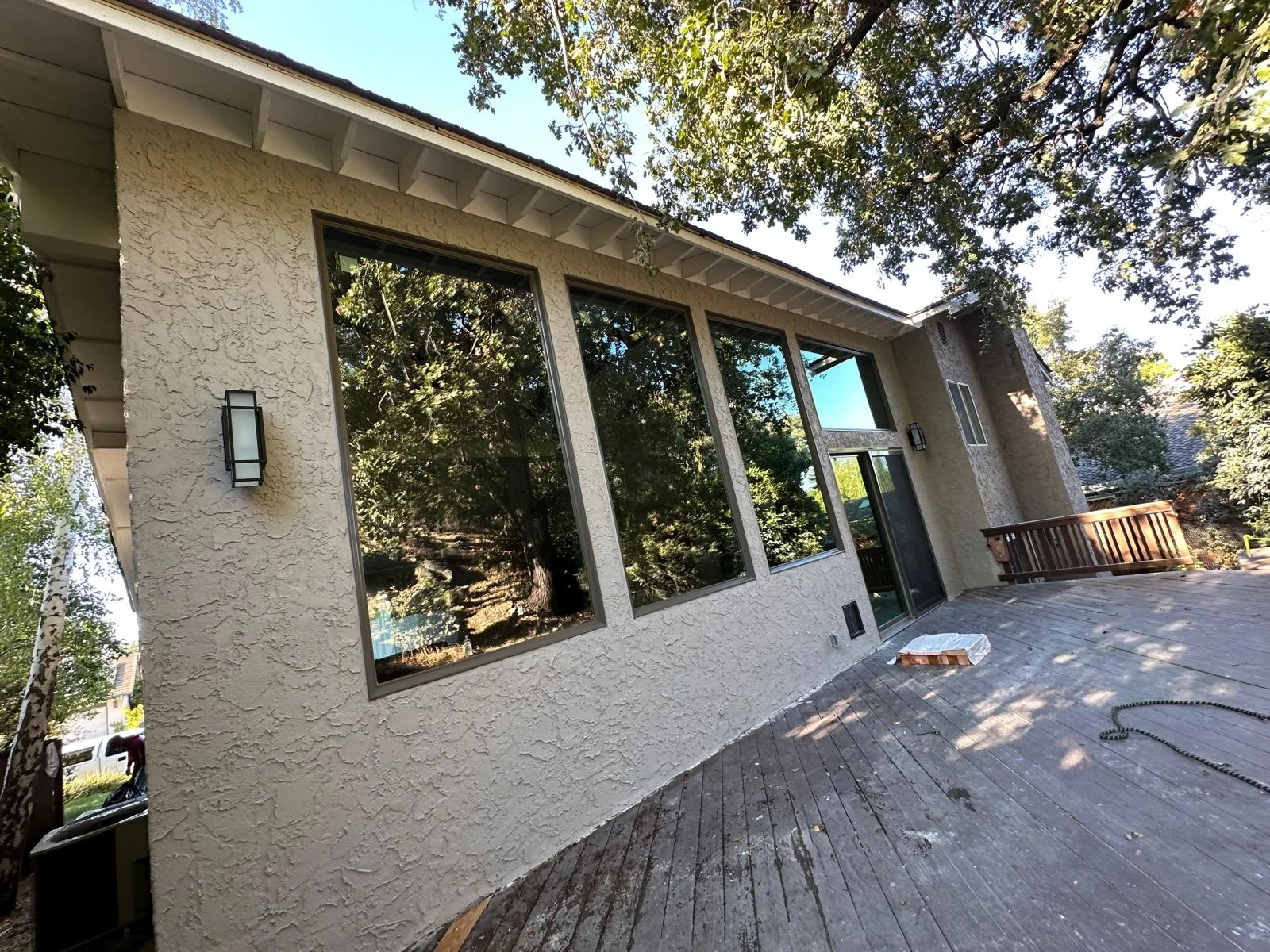Stucco exterior with large black-framed windows and composite deck