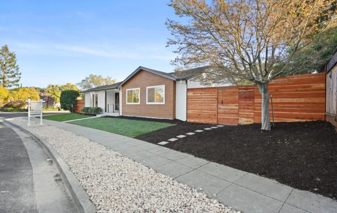 Modern home with cedar siding, horizontal wood fence, gravel and paver entry, black mulch landscaping