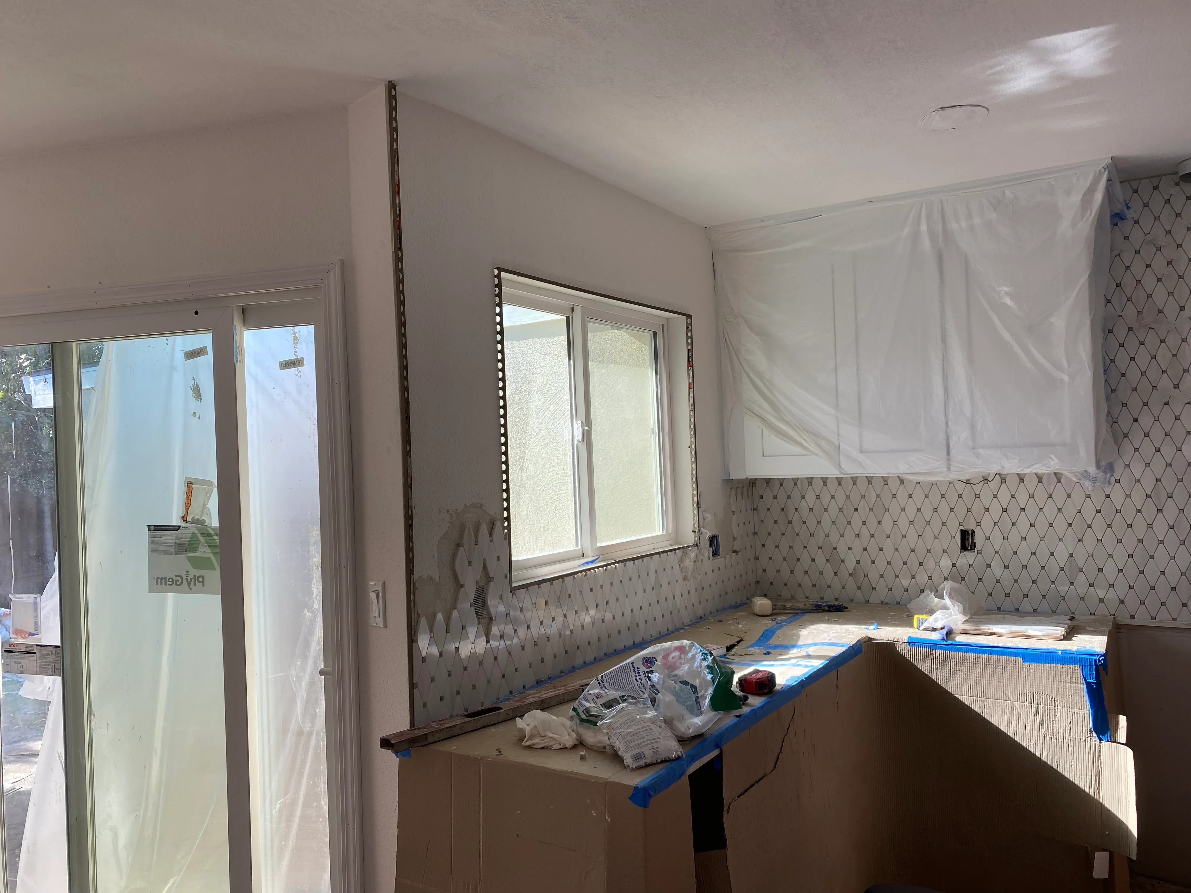 Kitchen remodeling in progress with new backsplash tile and cabinet work