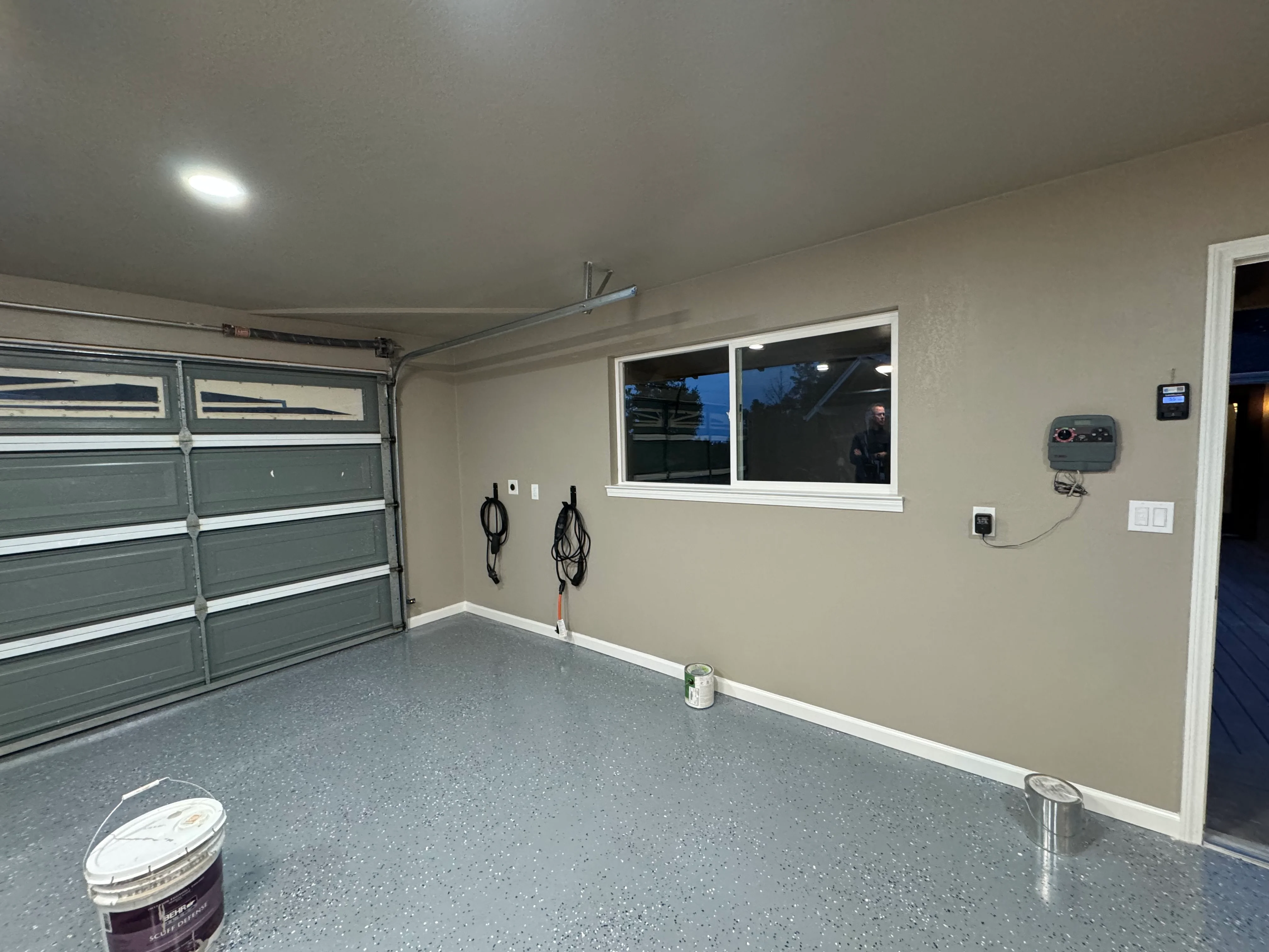 Finished garage with epoxy flooring, painted drywall, recessed lighting, and modern garage door