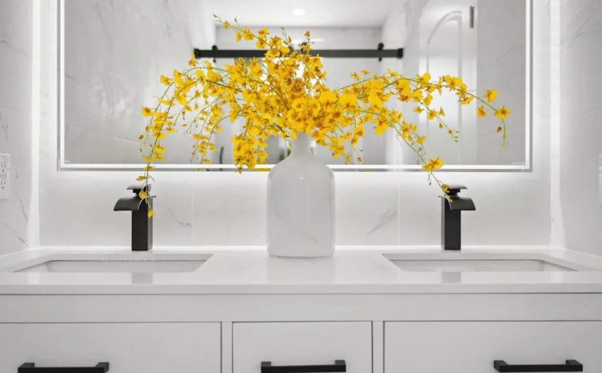 Dual sink bathroom vanity with white quartz countertop, black faucets, and marble tile backsplash
