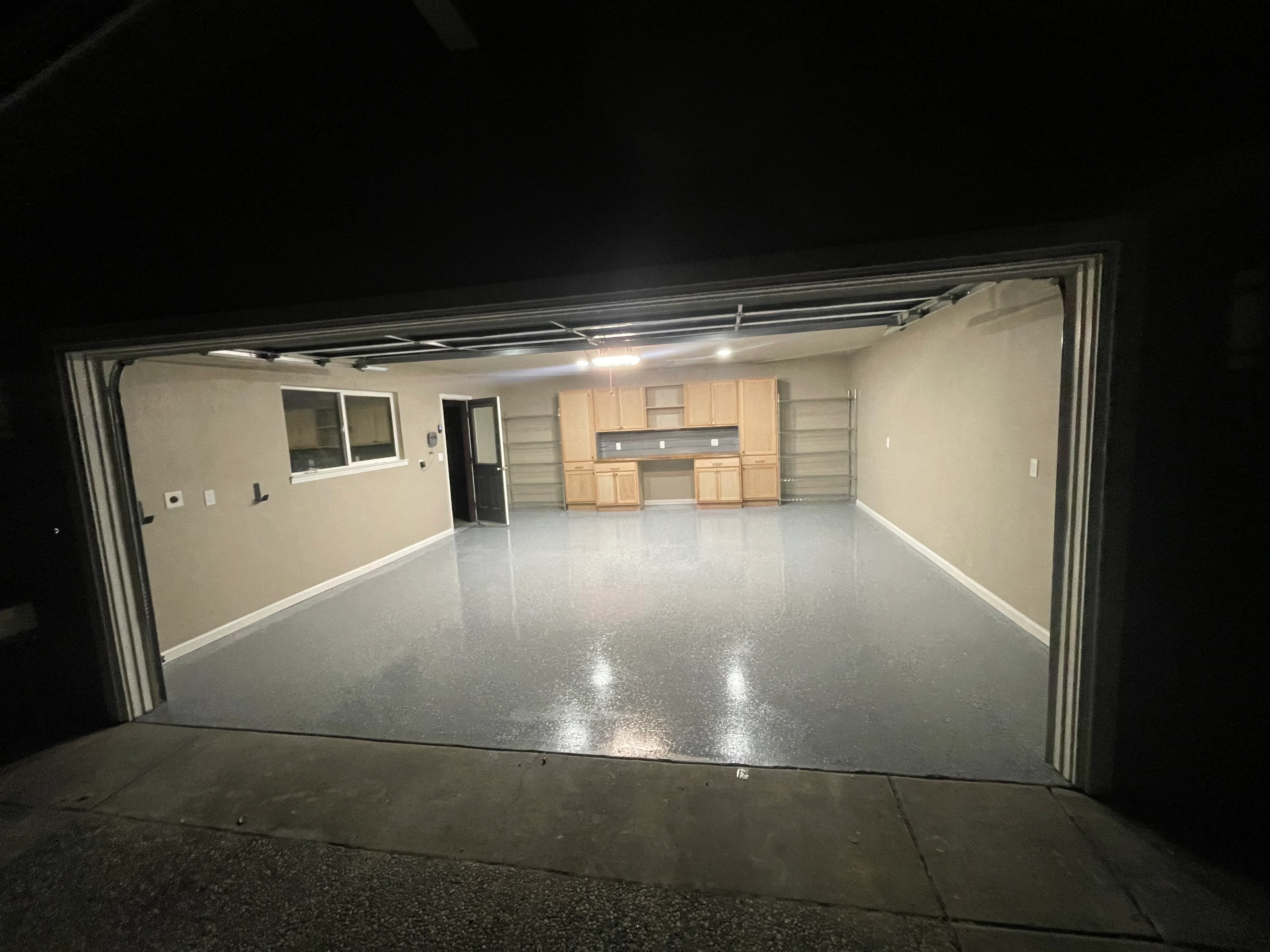 Polished epoxy concrete garage floor with finished drywall, LED lighting, and wood cabinetry