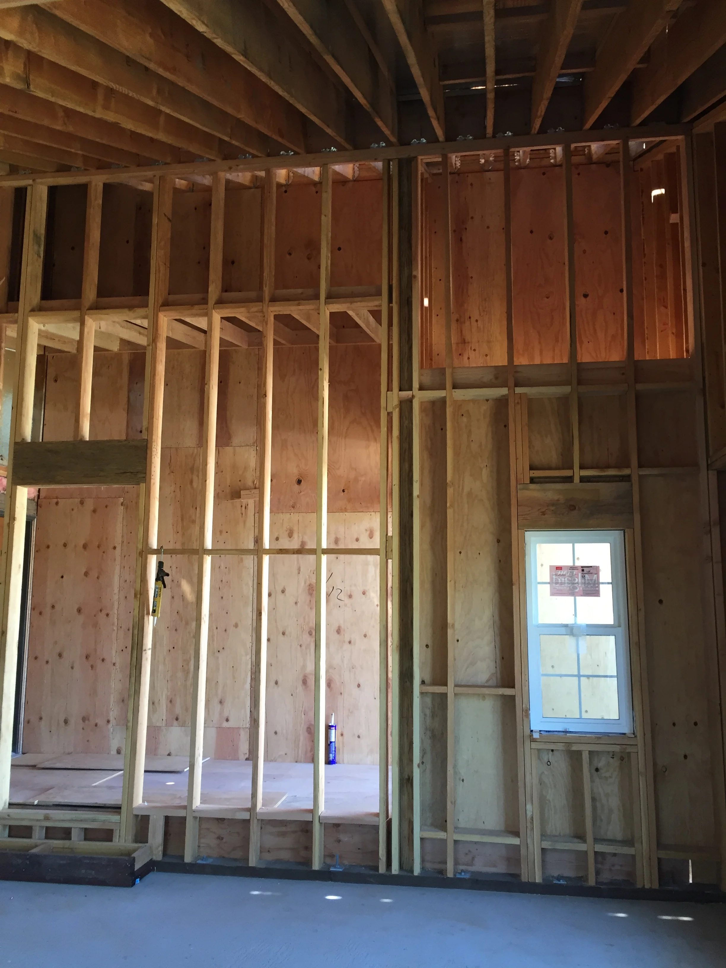 Interior framing with wood studs, plywood sheathing, and window opening in progress