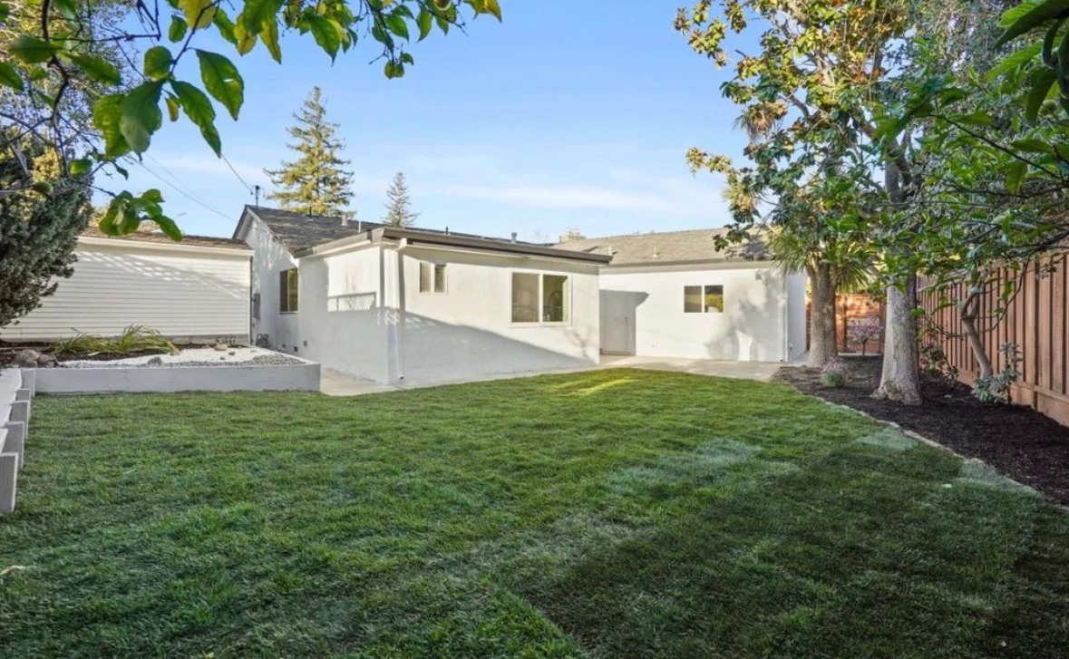 Cream stucco home with new windows, updated roof, fresh lawn, and wooden fence