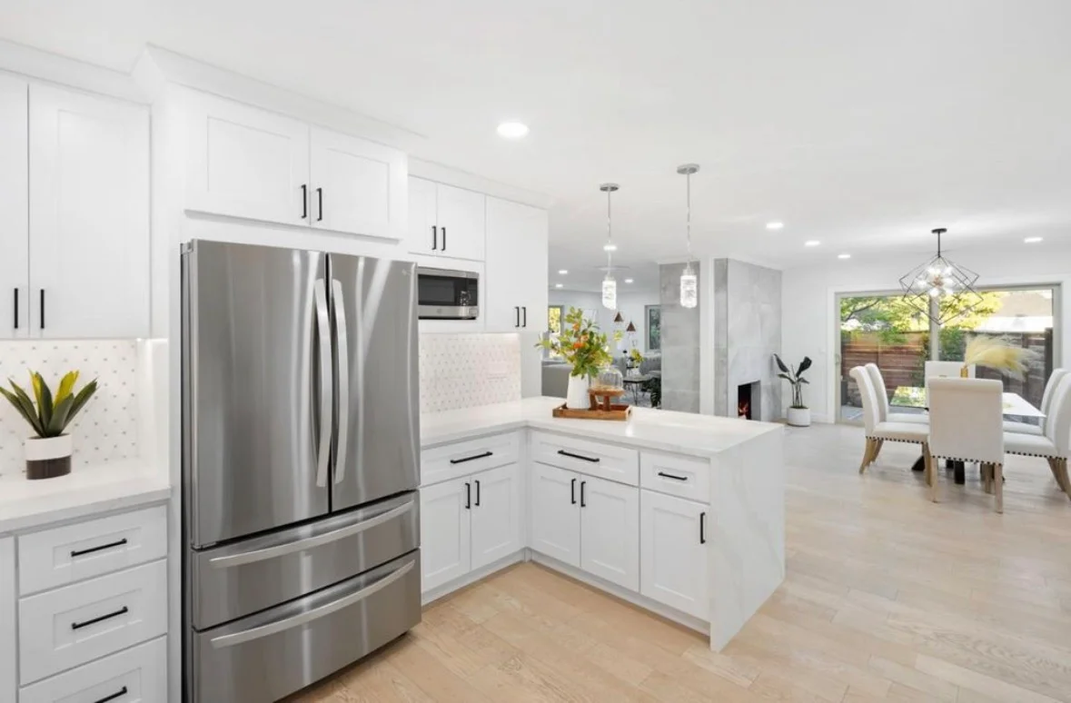 White kitchen with stainless steel appliances, island, quartz counters, and pendant lights