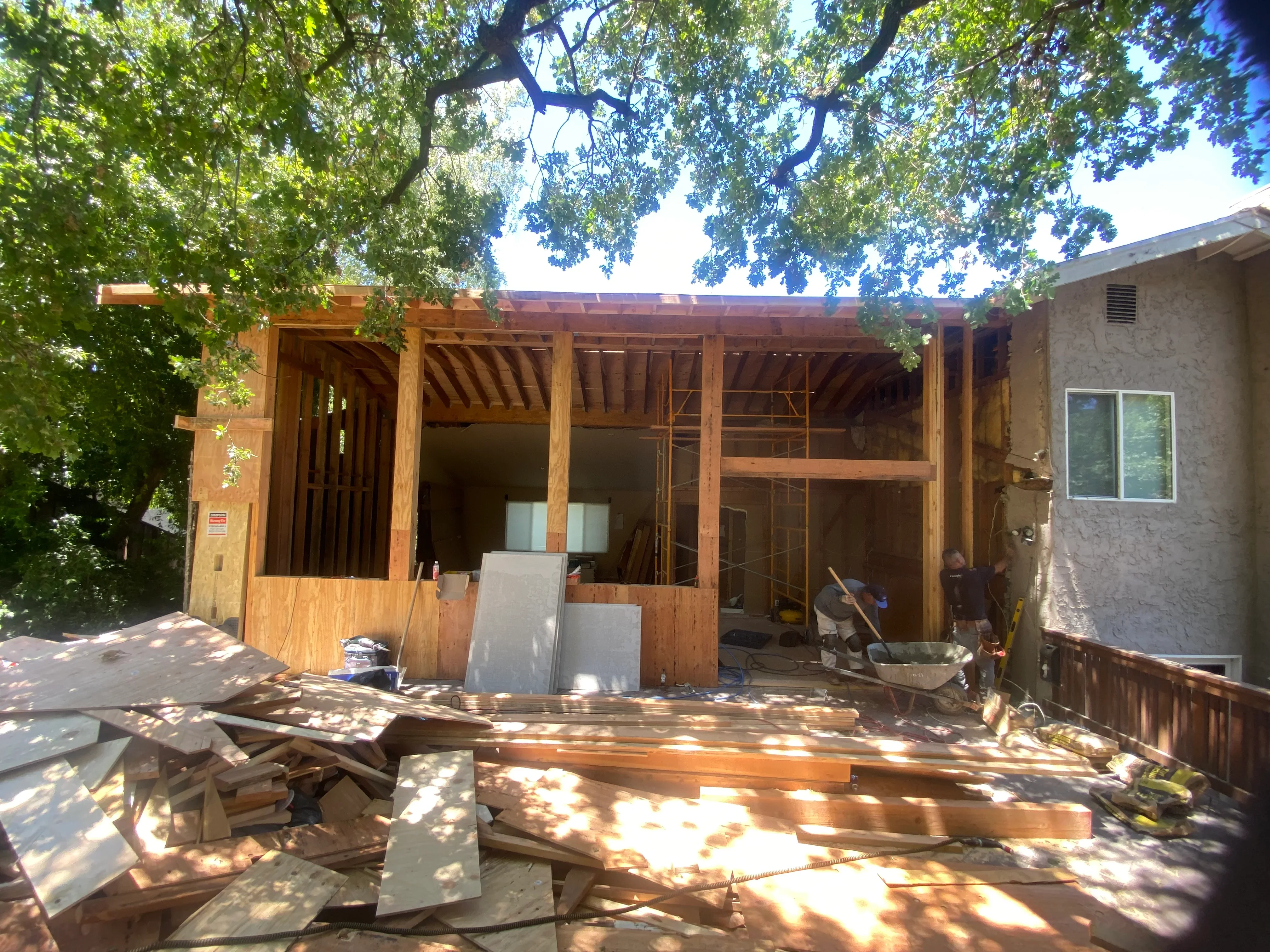Wood-framed residential addition under construction with exposed beams and window openings