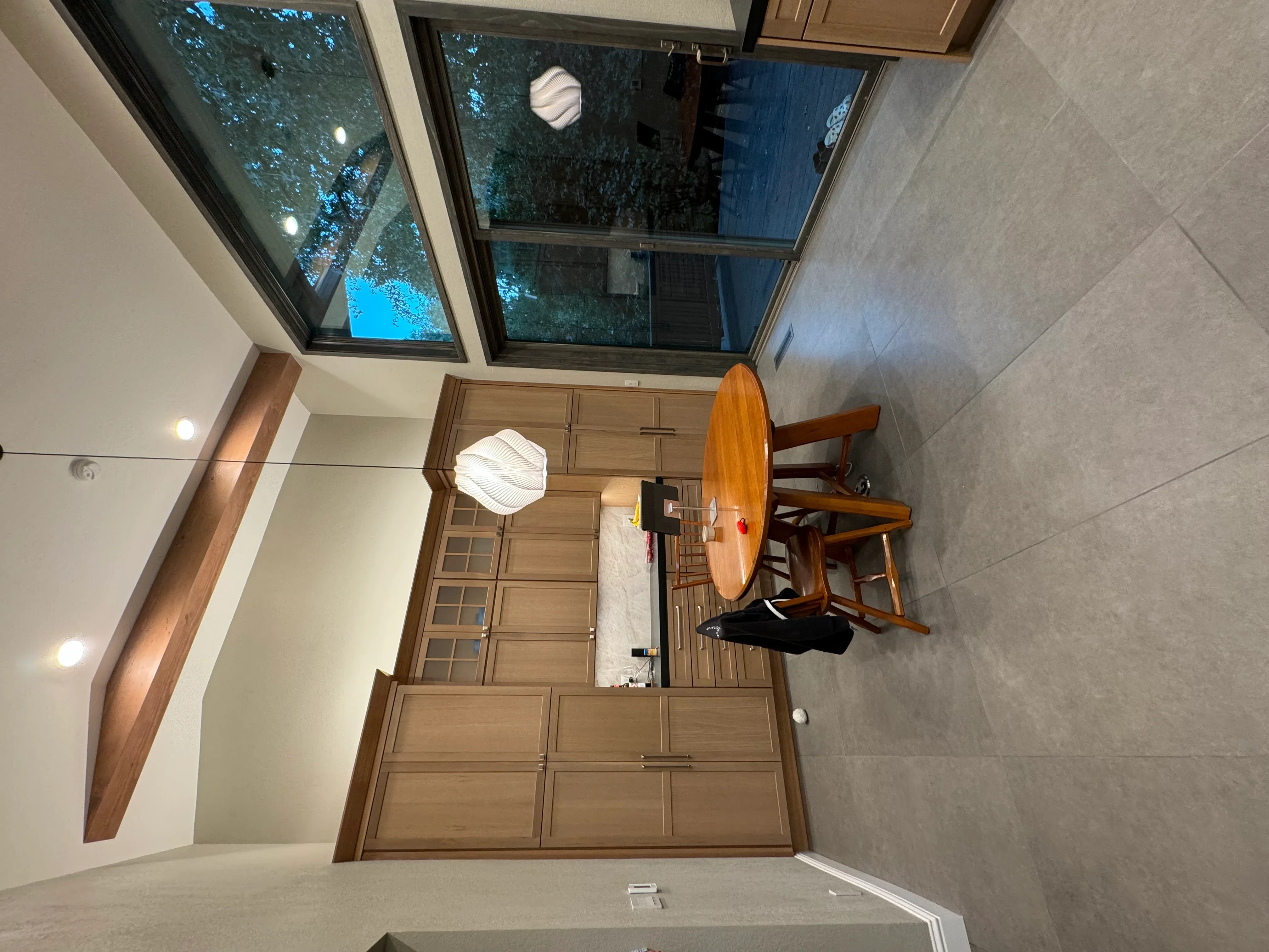 Modern interior room with gray tile flooring, wood cabinetry, and skylights overhead