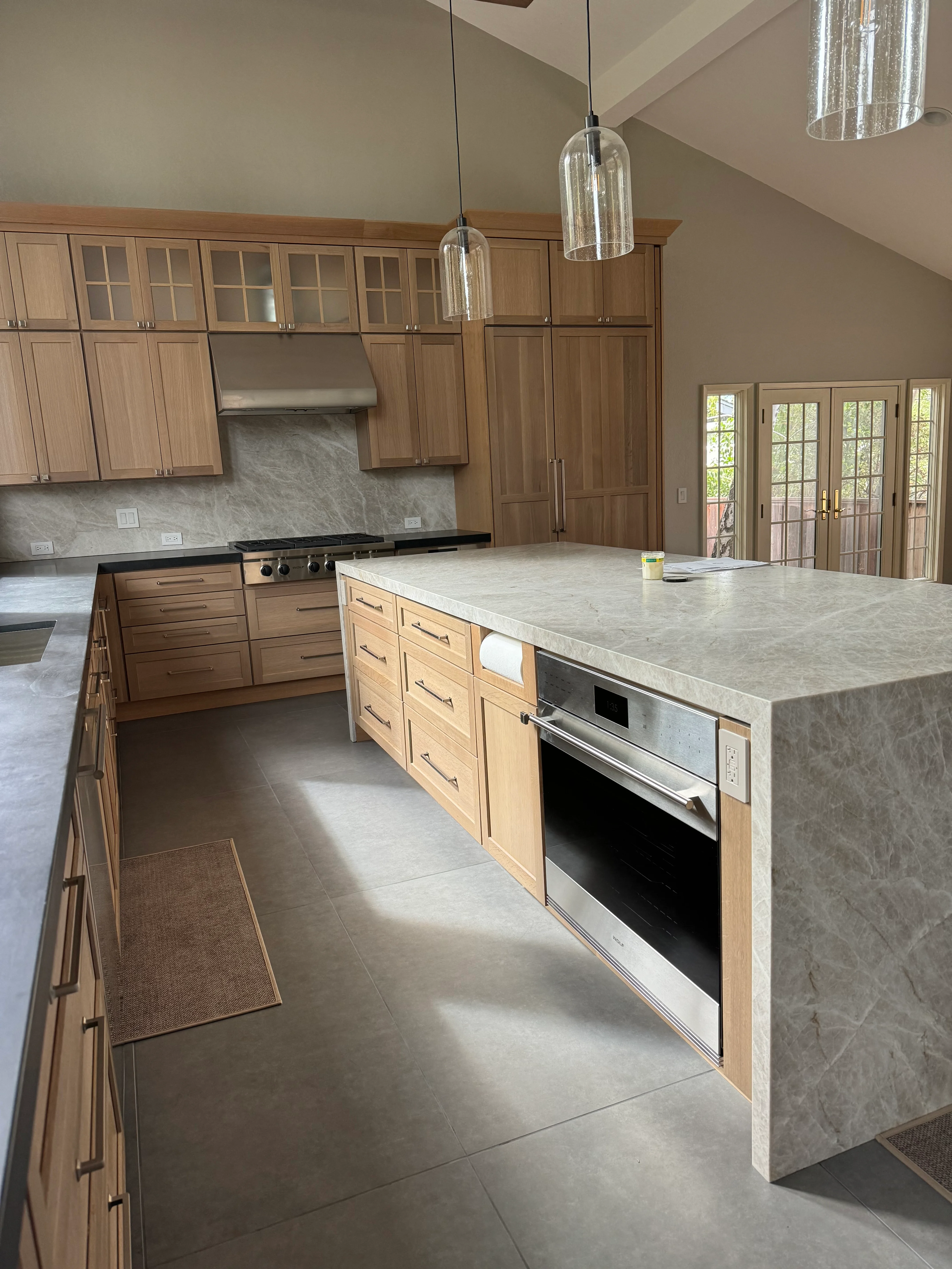 Kitchen with wood cabinetry, quartz countertops, island, stainless appliances, and pendant lights