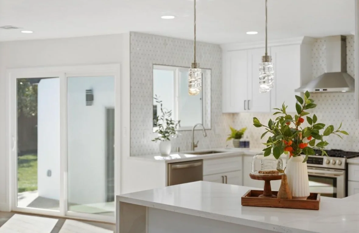 Modern kitchen with white cabinetry, quartz counters, stainless steel appliances, and pendant lights
