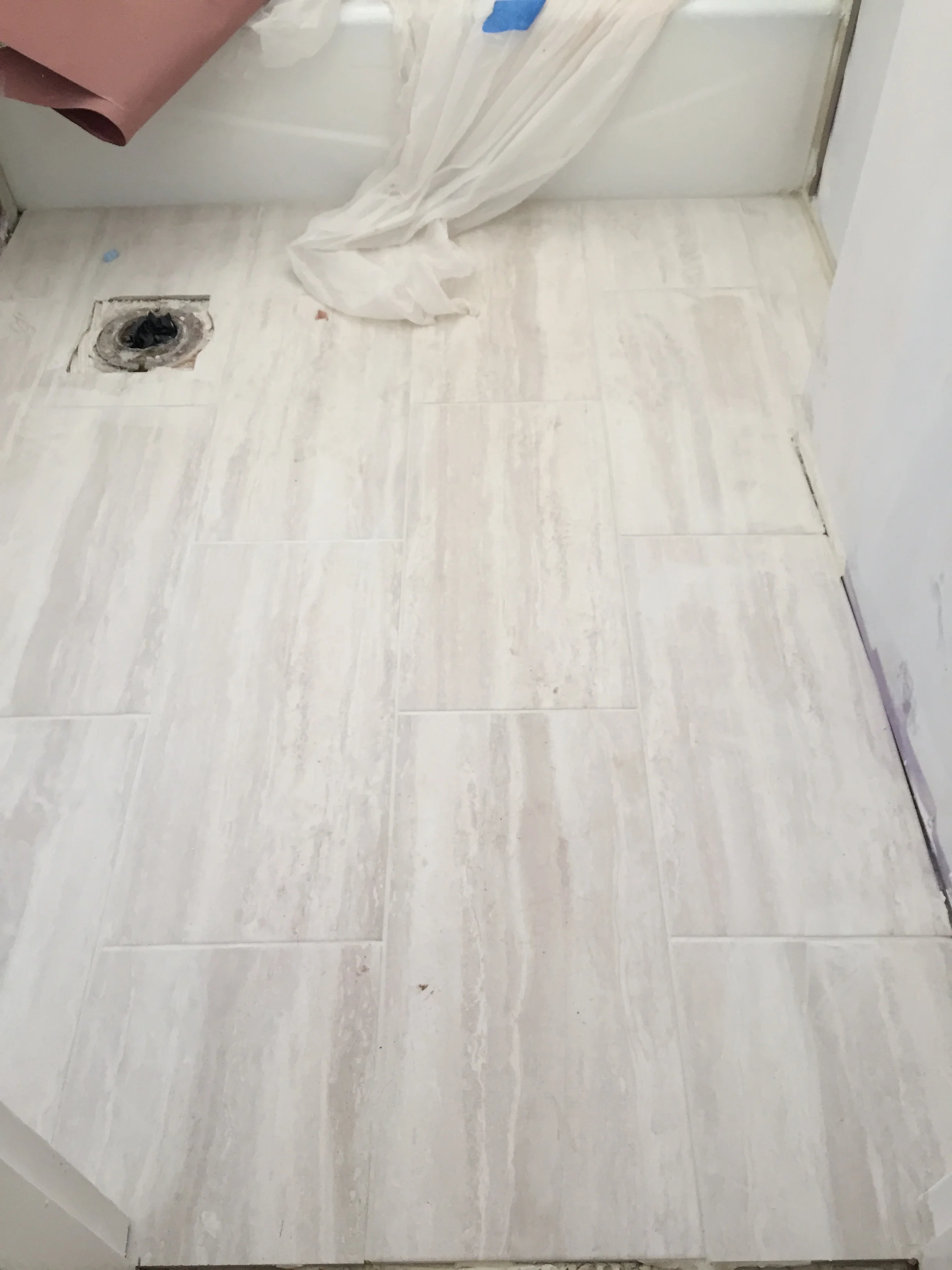 White wood-grain luxury vinyl plank flooring installation with recessed light opening and protective coverings
