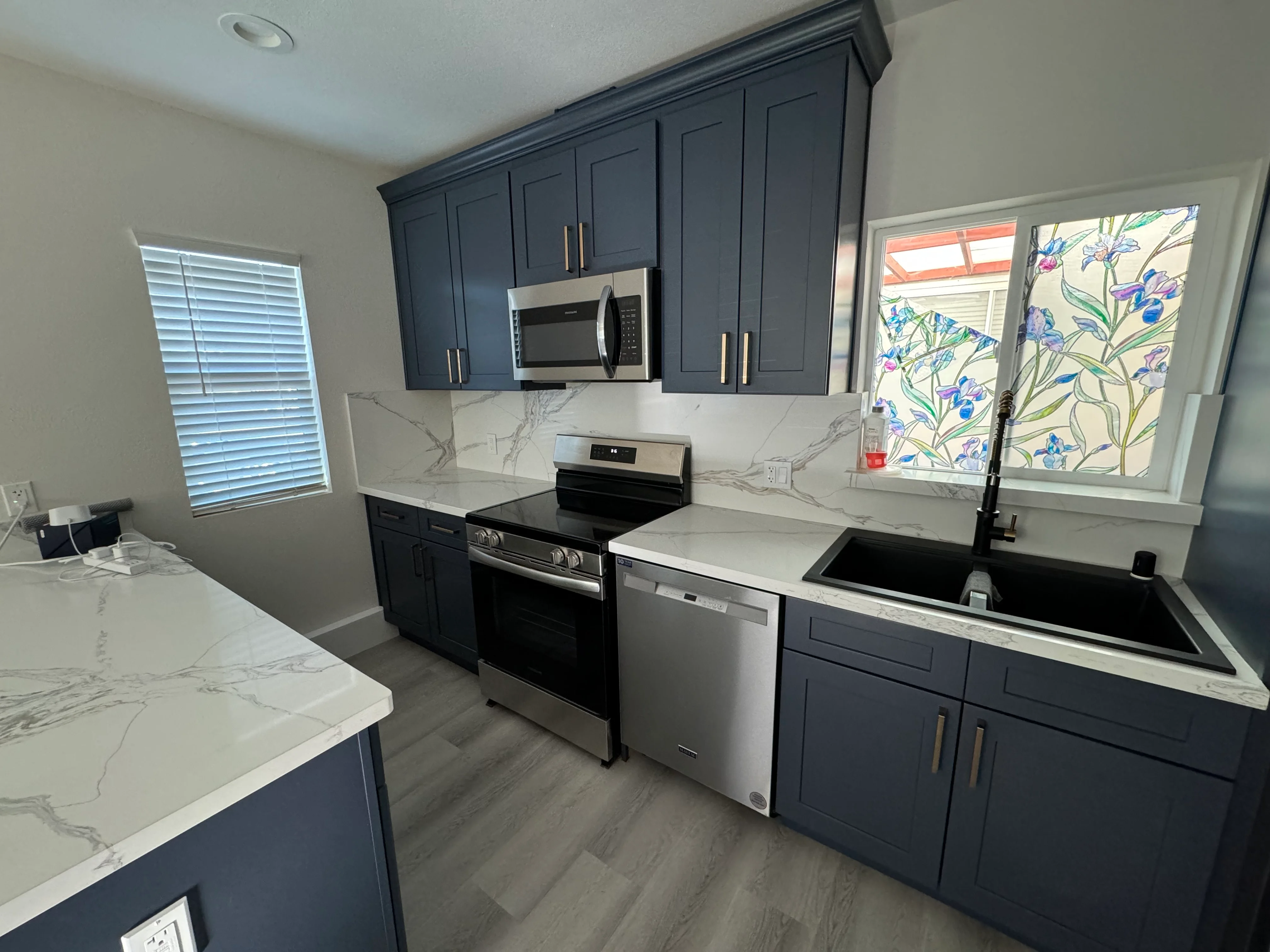 Dark navy kitchen cabinets with marble quartz countertops, stainless steel appliances, and island