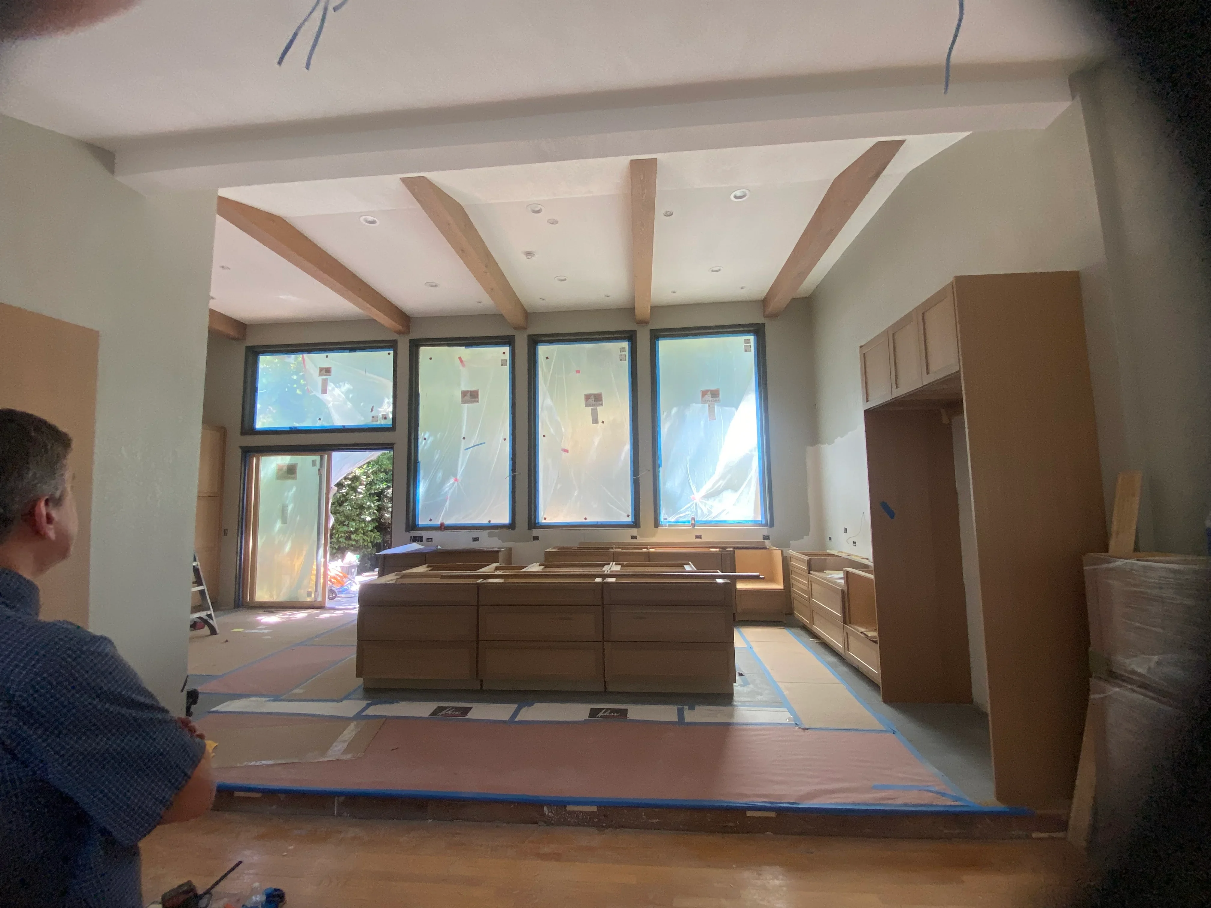 Modern kitchen with exposed wood beams, white ceiling, and custom wood cabinetry under construction