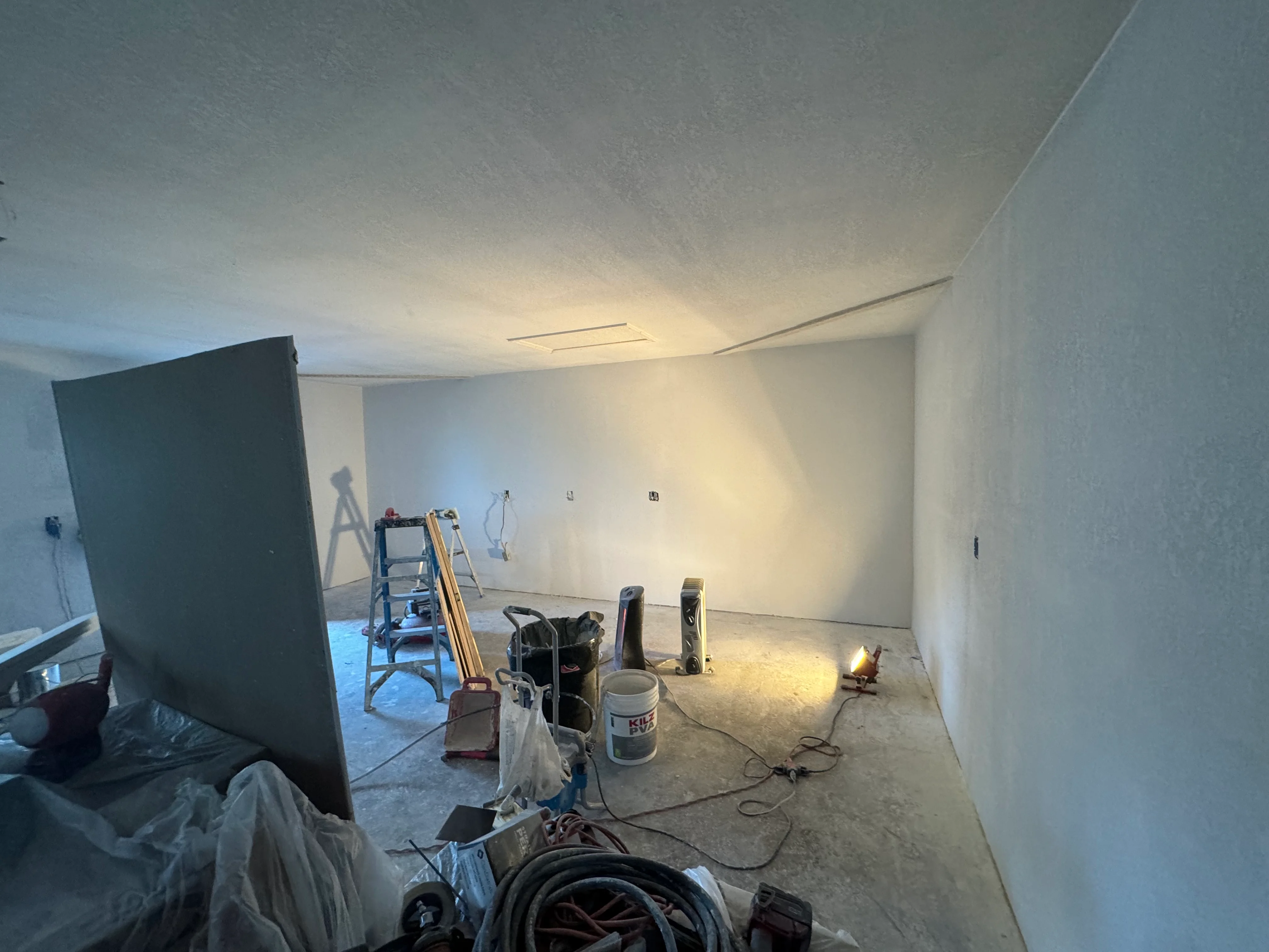 Interior room with drywall installation, recessed lighting, and finishing work in progress