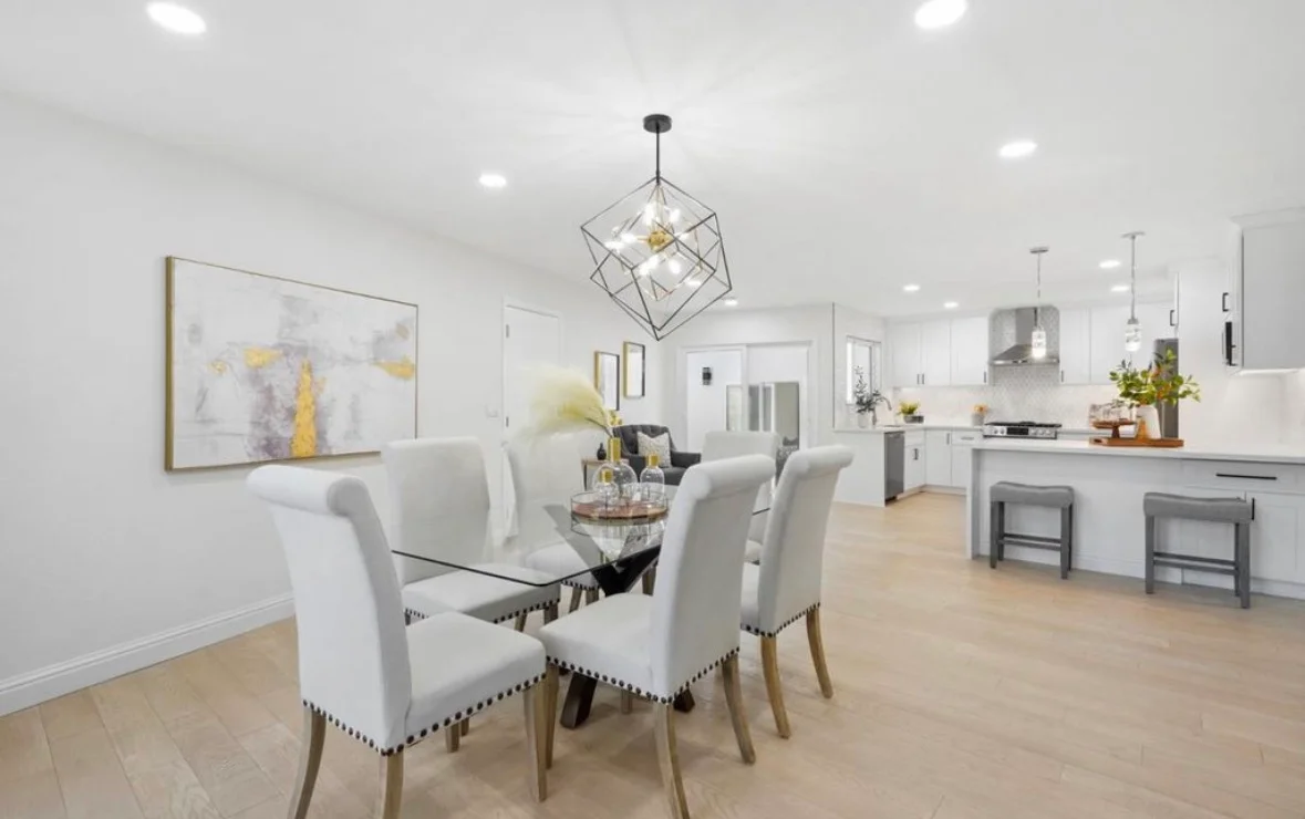 Modern kitchen and dining area with white cabinetry, quartz counters, stainless steel appliances, and light wood flooring