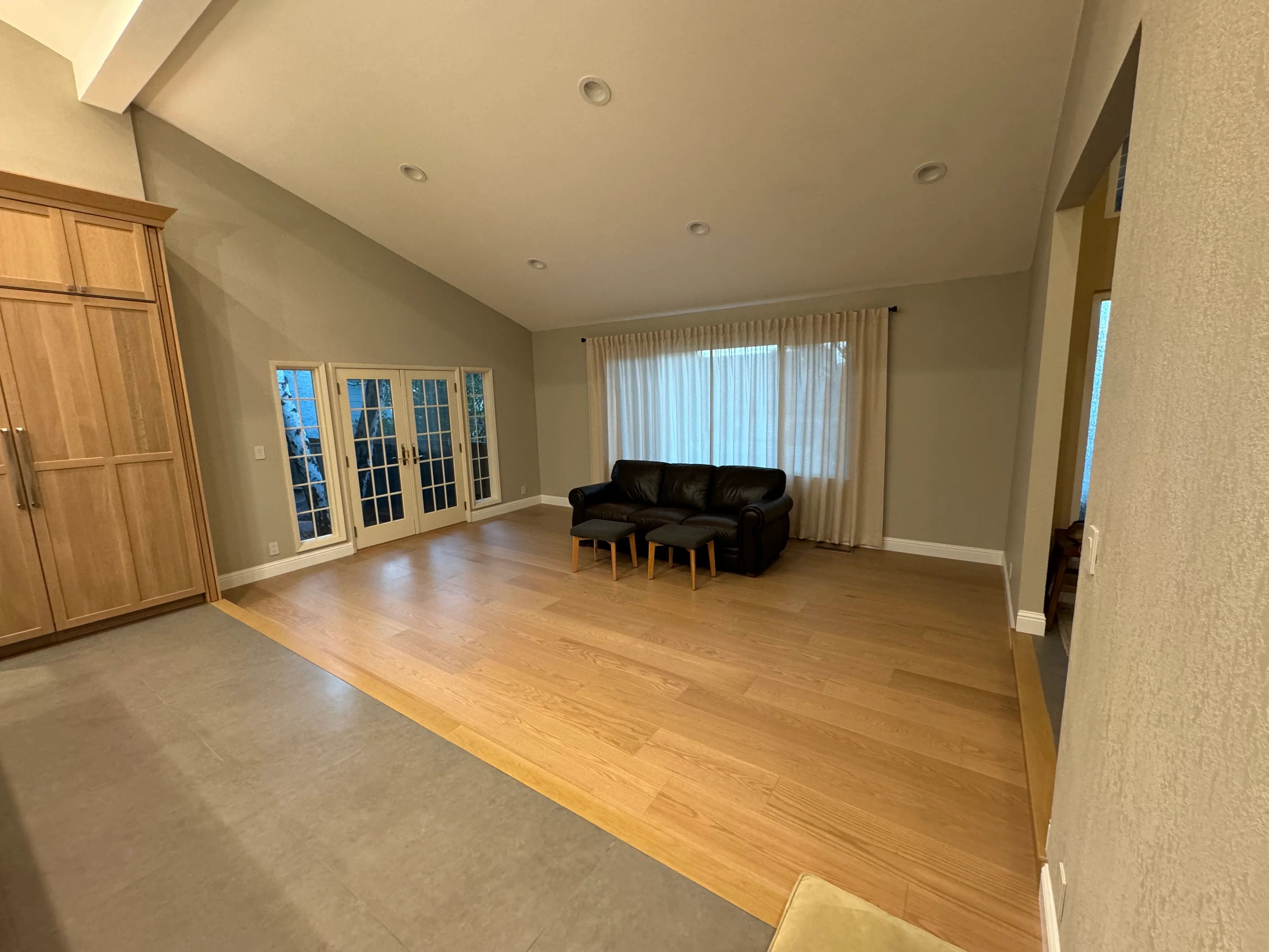 Open living room with hardwood flooring, recessed lighting, French doors, and neutral walls