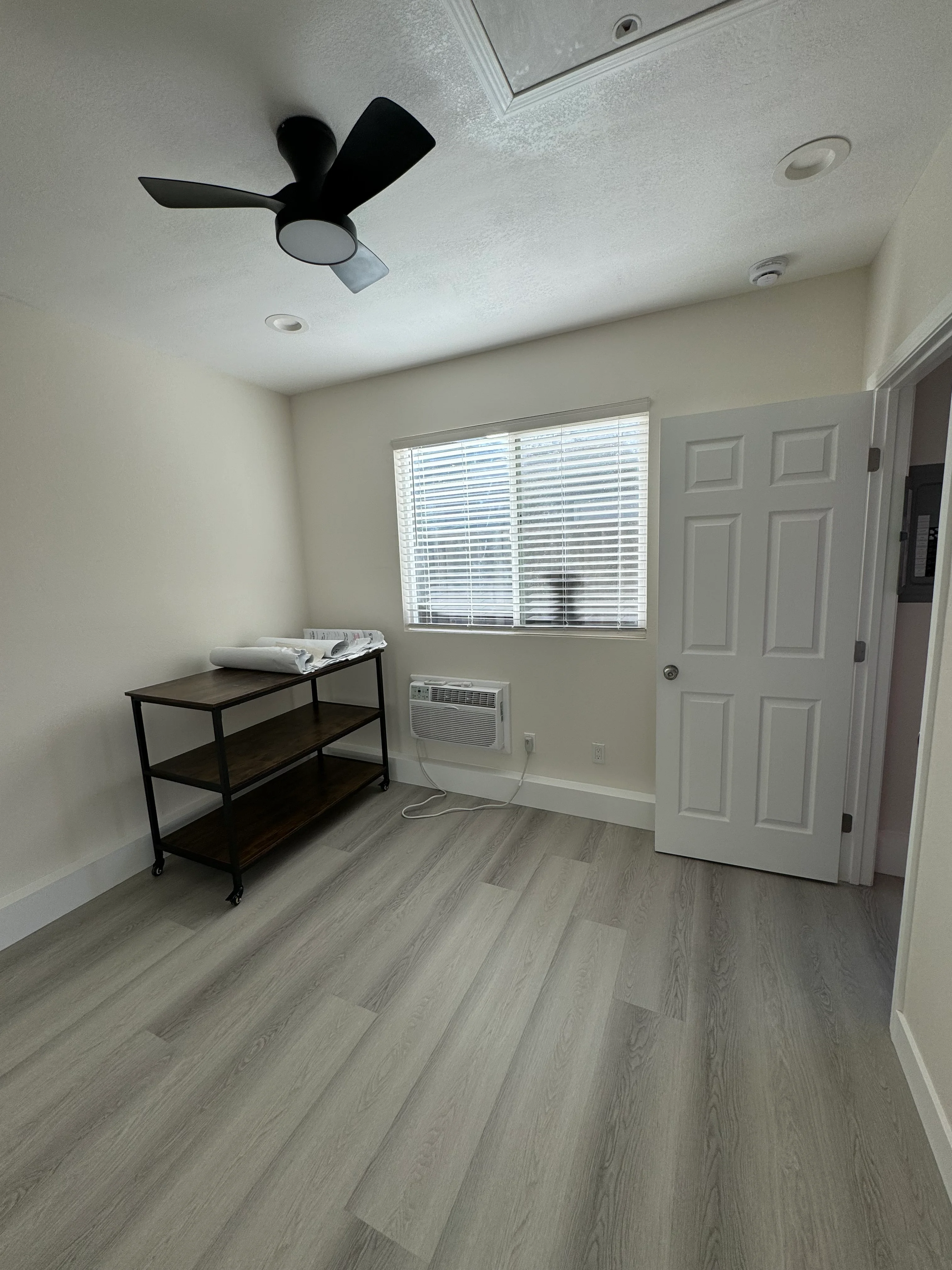 Bedroom with gray vinyl plank flooring, white drywall ceiling, black ceiling fan, recessed lights, and six-panel doors