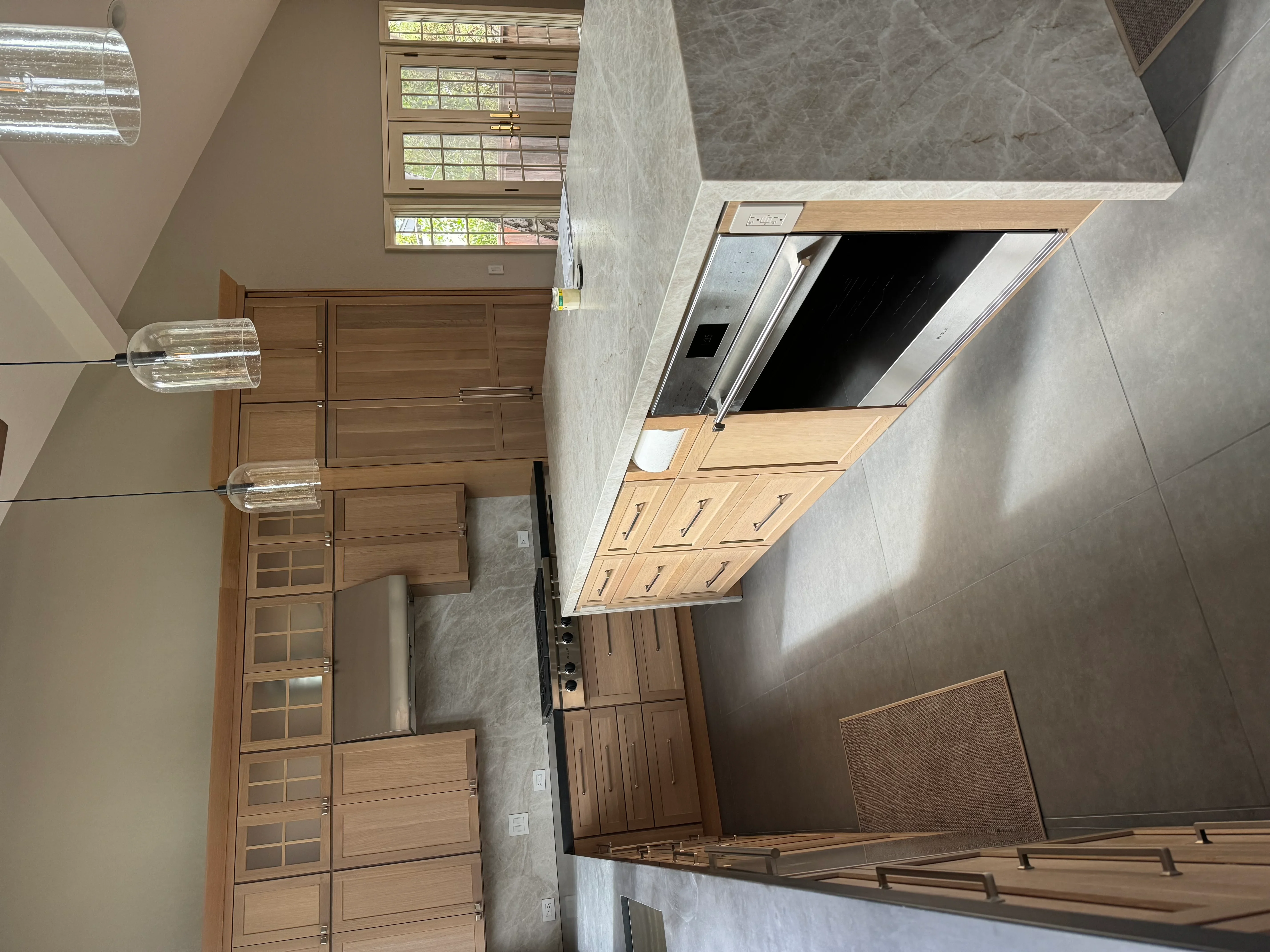 Modern kitchen with wood cabinets, gray quartz counters, and stainless steel appliances