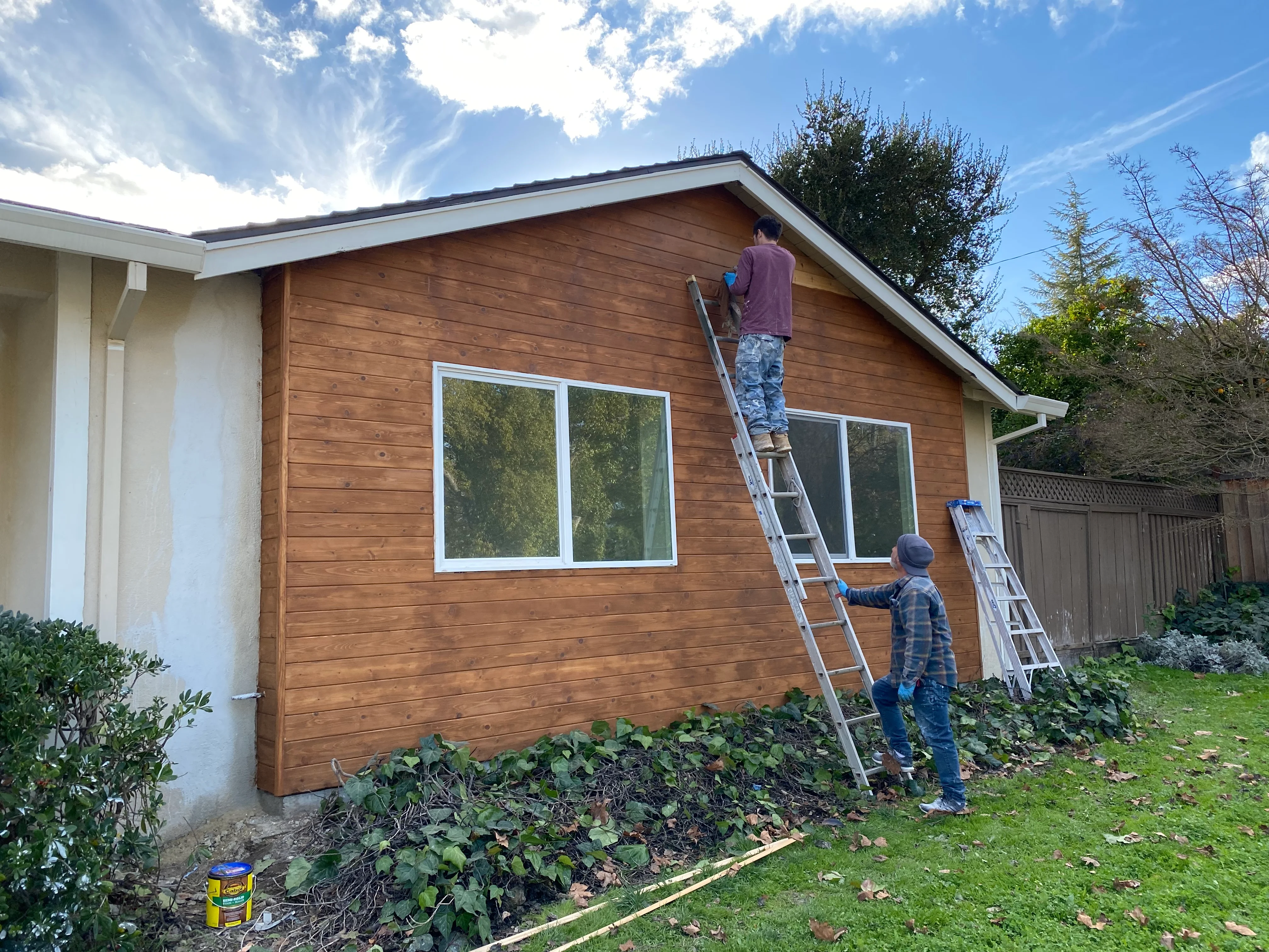 Cedar siding installation with white-trimmed windows on residential exterior renovation