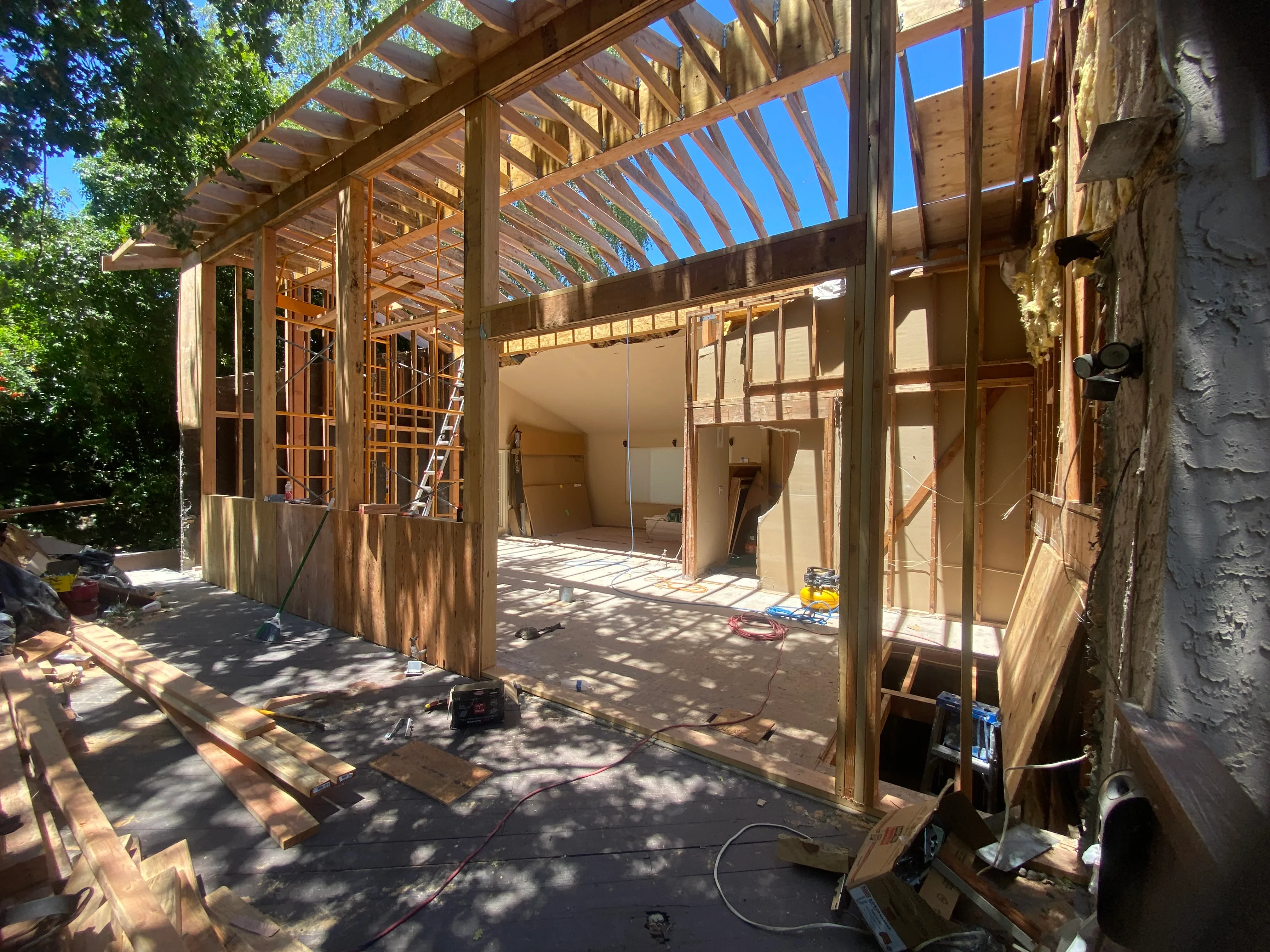 Wood-framed residential addition under construction with exposed beams and clerestory windows
