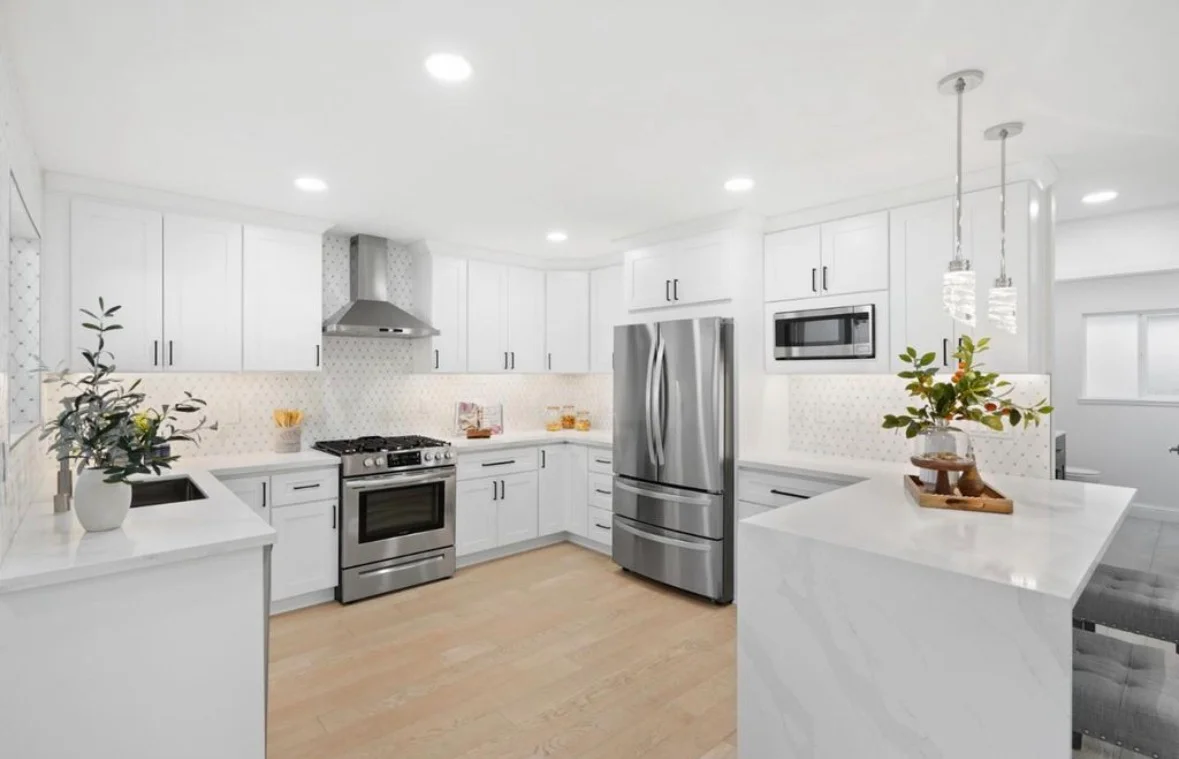 White kitchen with shaker cabinets, quartz counters, geometric backsplash, and stainless steel appliances