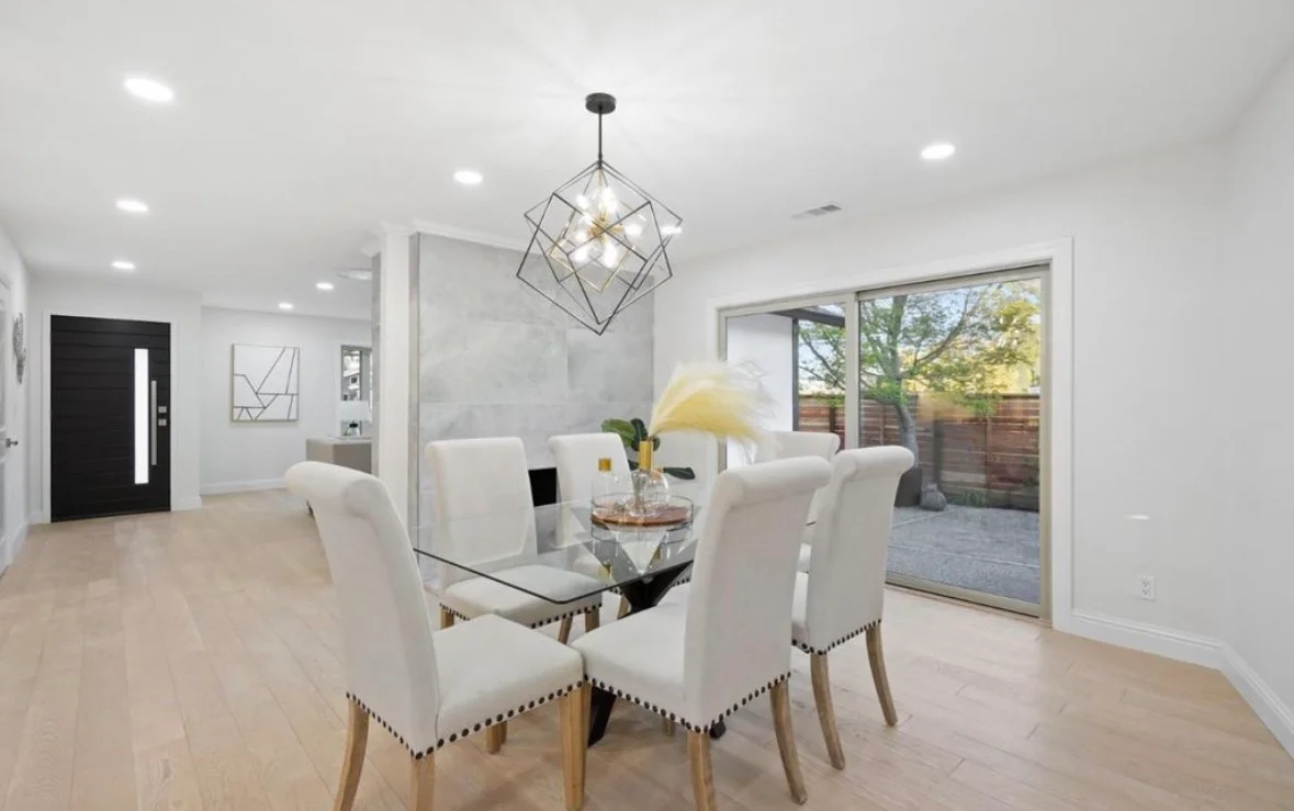 Open-concept dining room with wood flooring, geometric pendant light, and sliding glass doors to patio