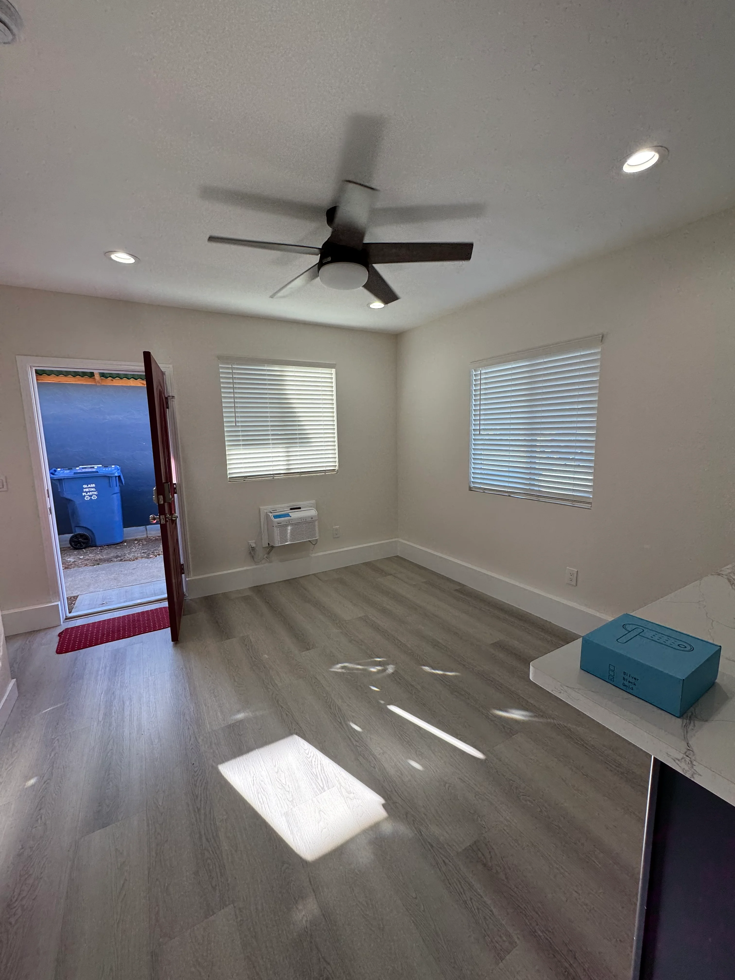 Interior room with gray vinyl plank flooring, white drywall, black ceiling fan, and recessed lighting